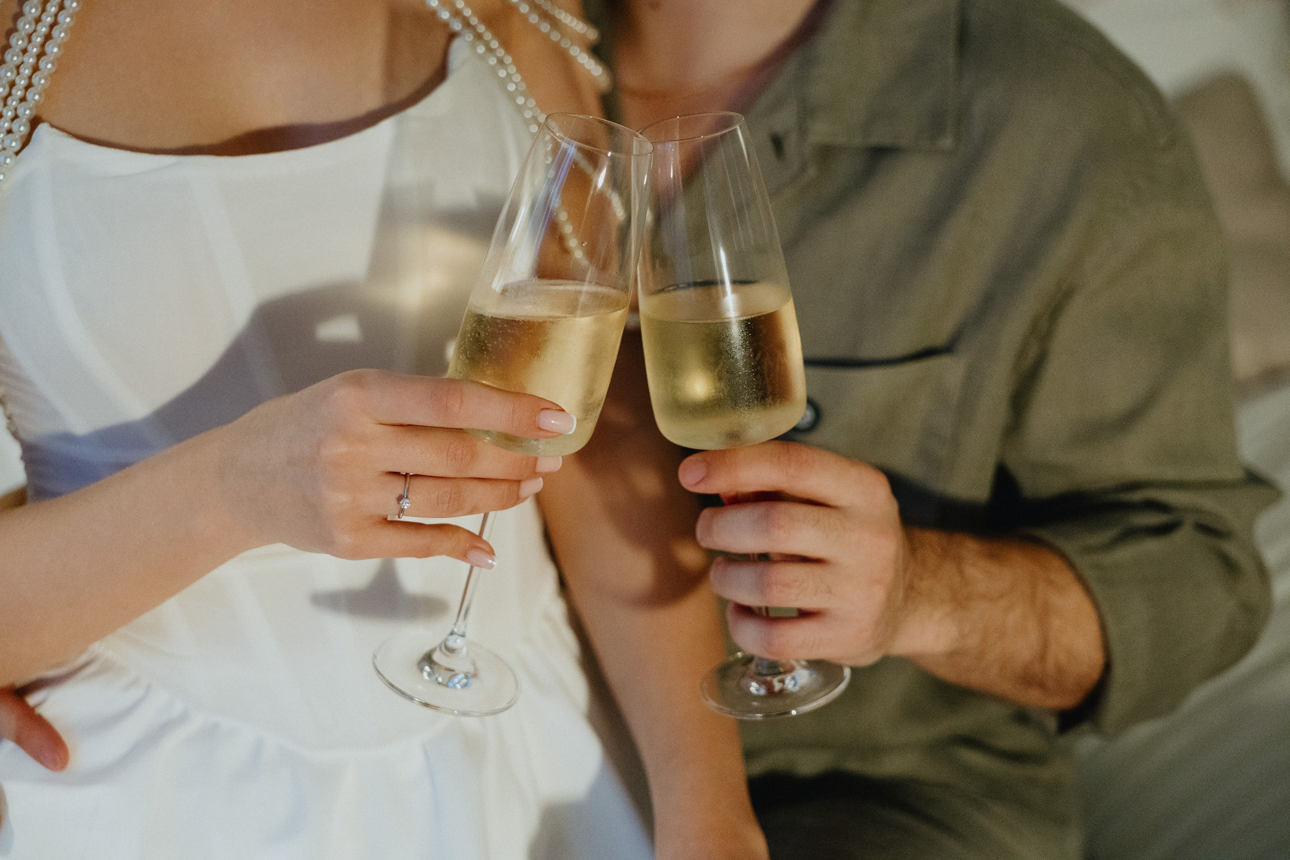 Невеста и жених держат бокалы с шампанским, улыбаясь друг другу.