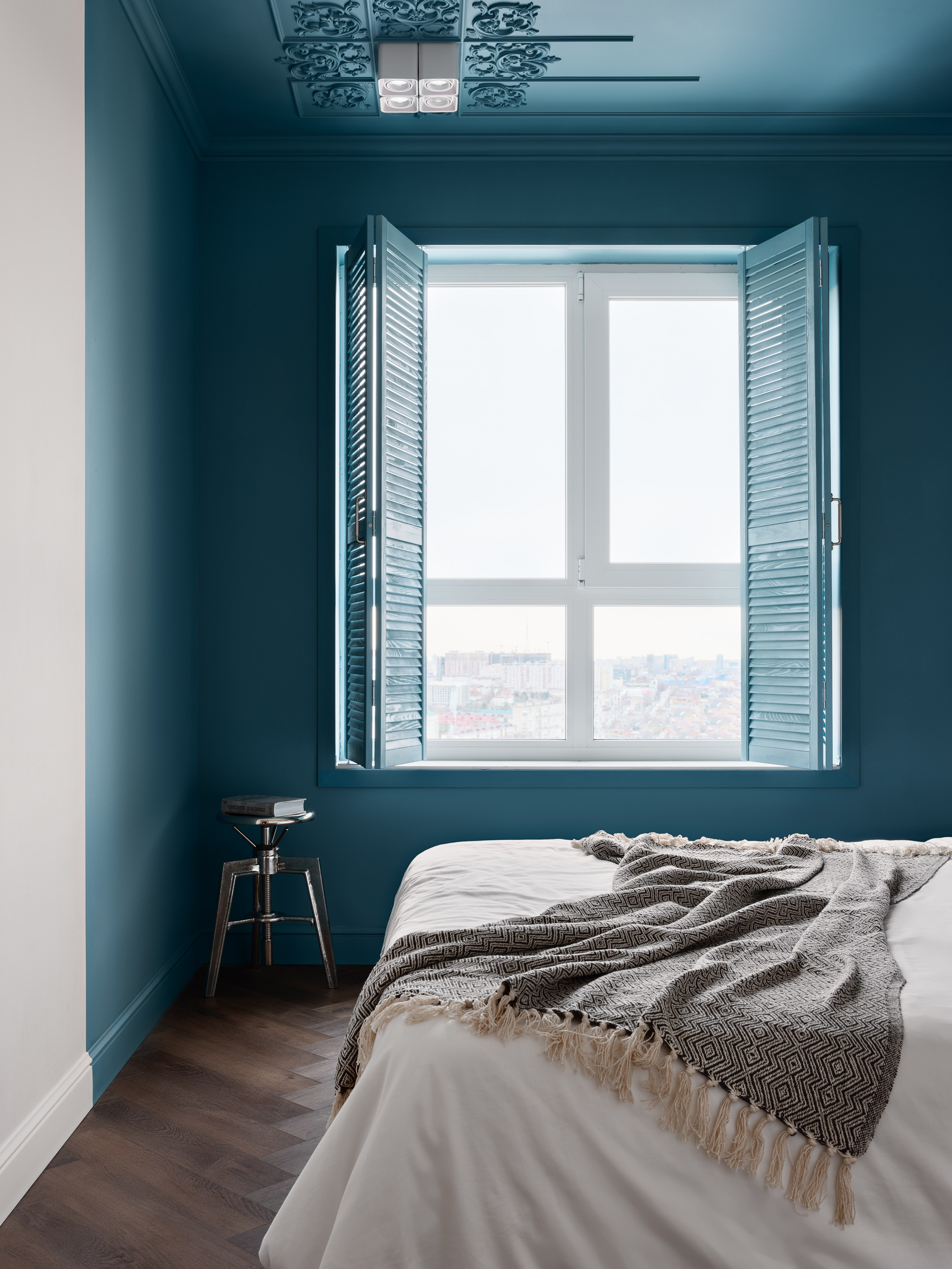Просторная спальня с глубоким синим оттенком стен и потолка, декоративными элементами, большим окном с видом на город и контрастным текстилем. Дизайнер Антон Логинов, стилист Алёна Мощенская, фотограф Сергей Денисенко передали атмосферу уюта.