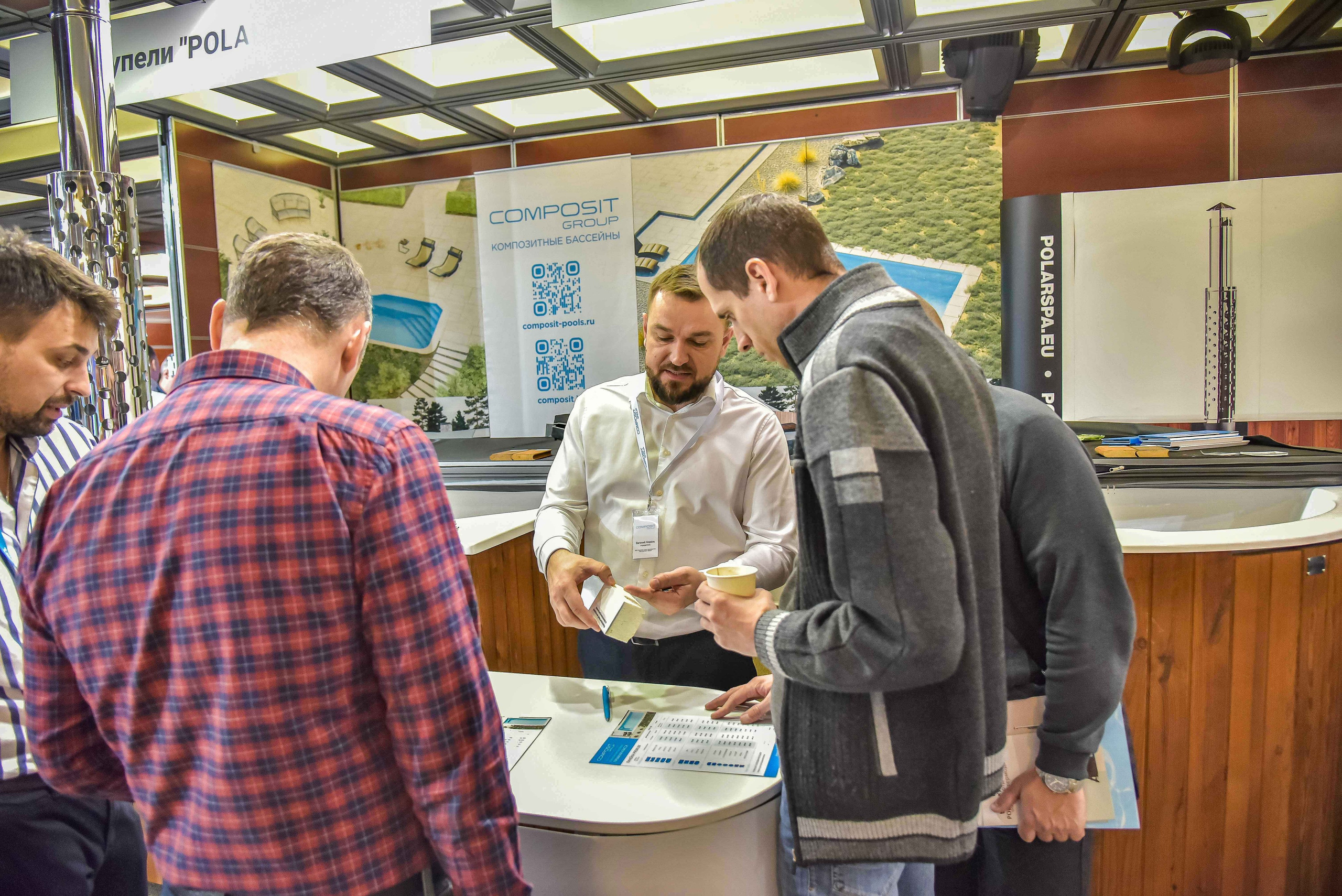Репортажная съемка с выставки в Москве: снимок передаёт общение между представителем компании и посетителями выставки.