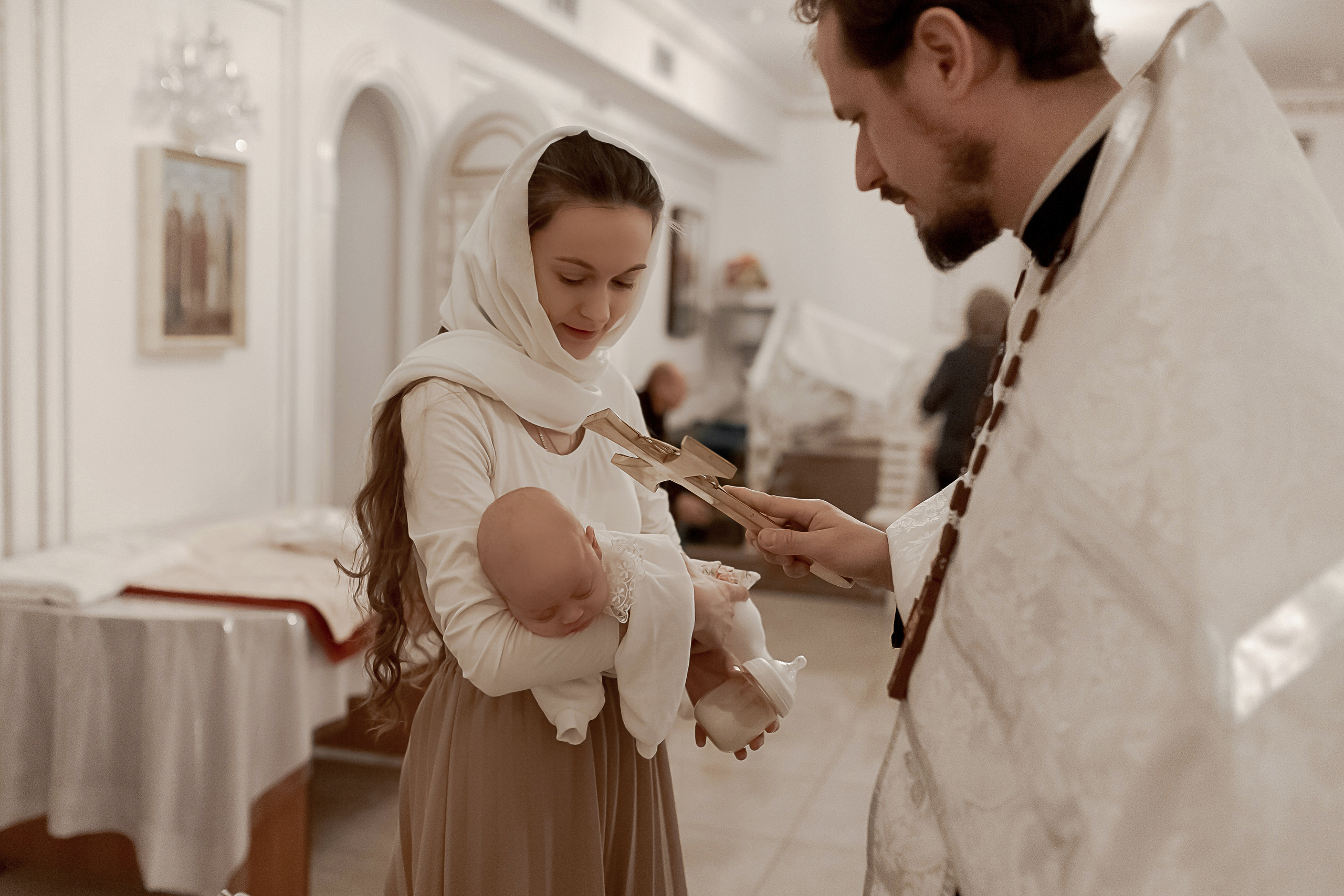священник благословляет ребенка после крестин в Ташкенте