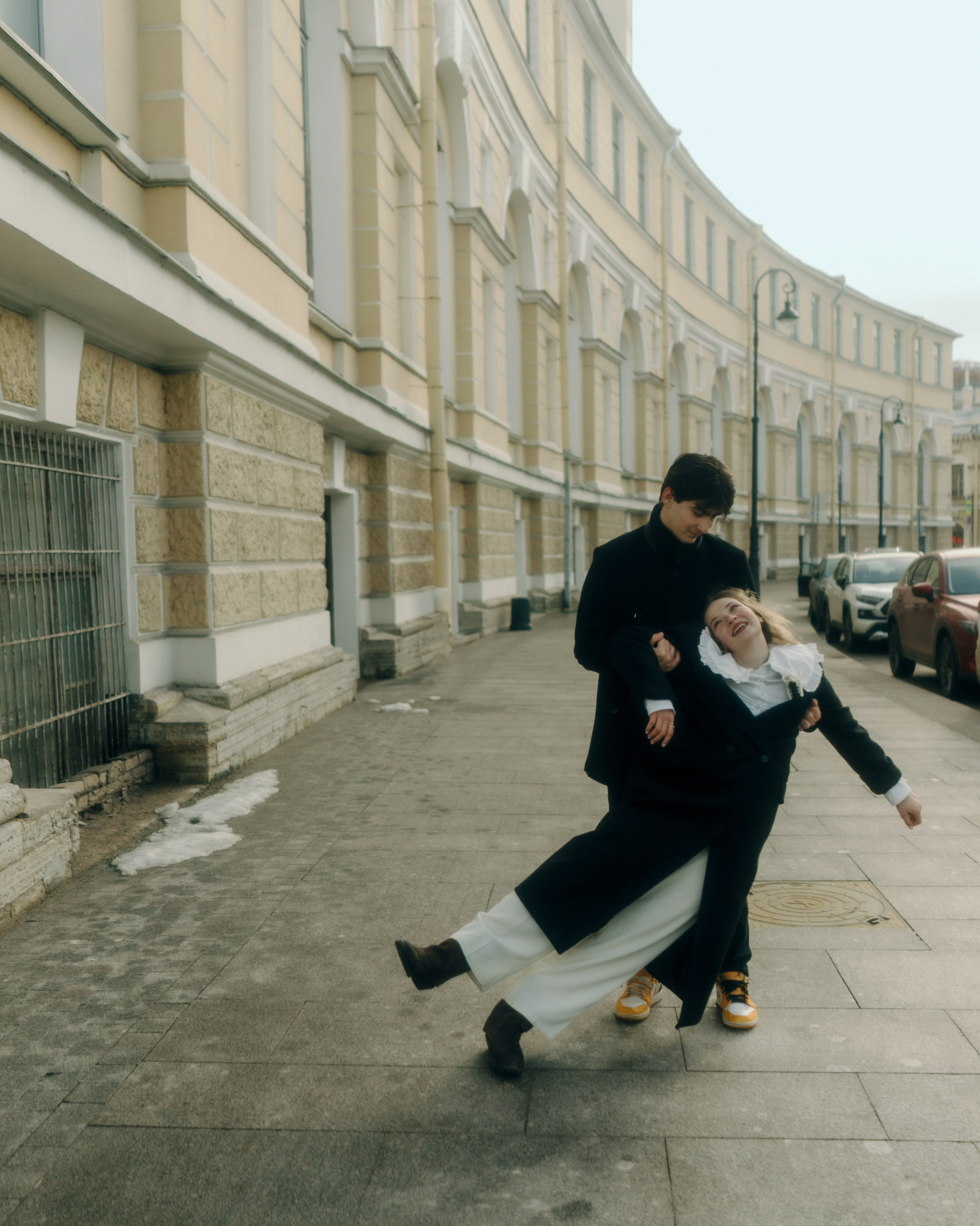 Фотосессия пары на тротуаре в Санкт-Петербурге, динамичный love story кадр с необычным движением, стилем и атмосферой авторского кино