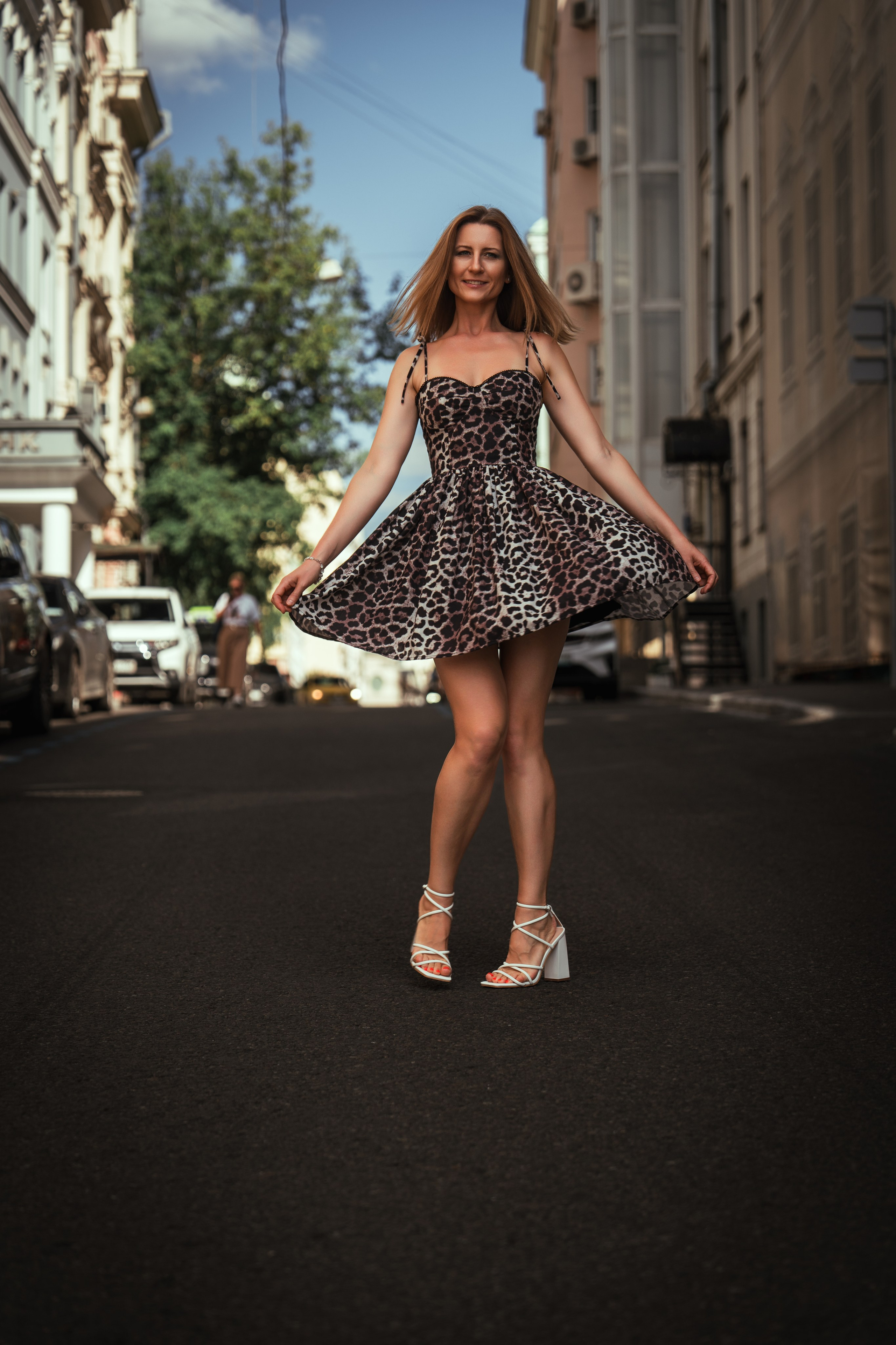 девушка в легком платье кружится по середине улицы Москвы