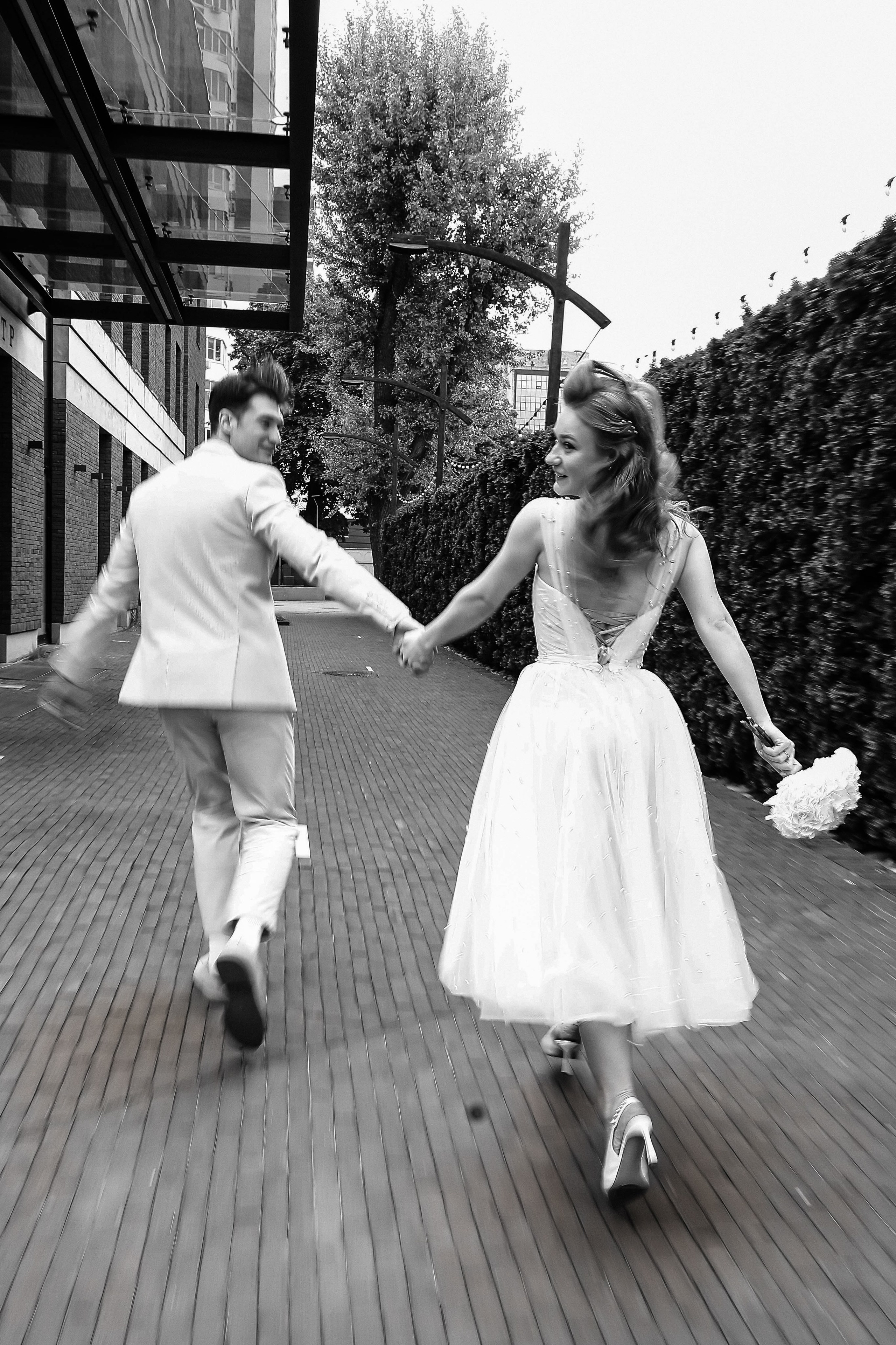 Жених и невста убегают во время свадебной фотосессии возле Камерного театра в Воронеже