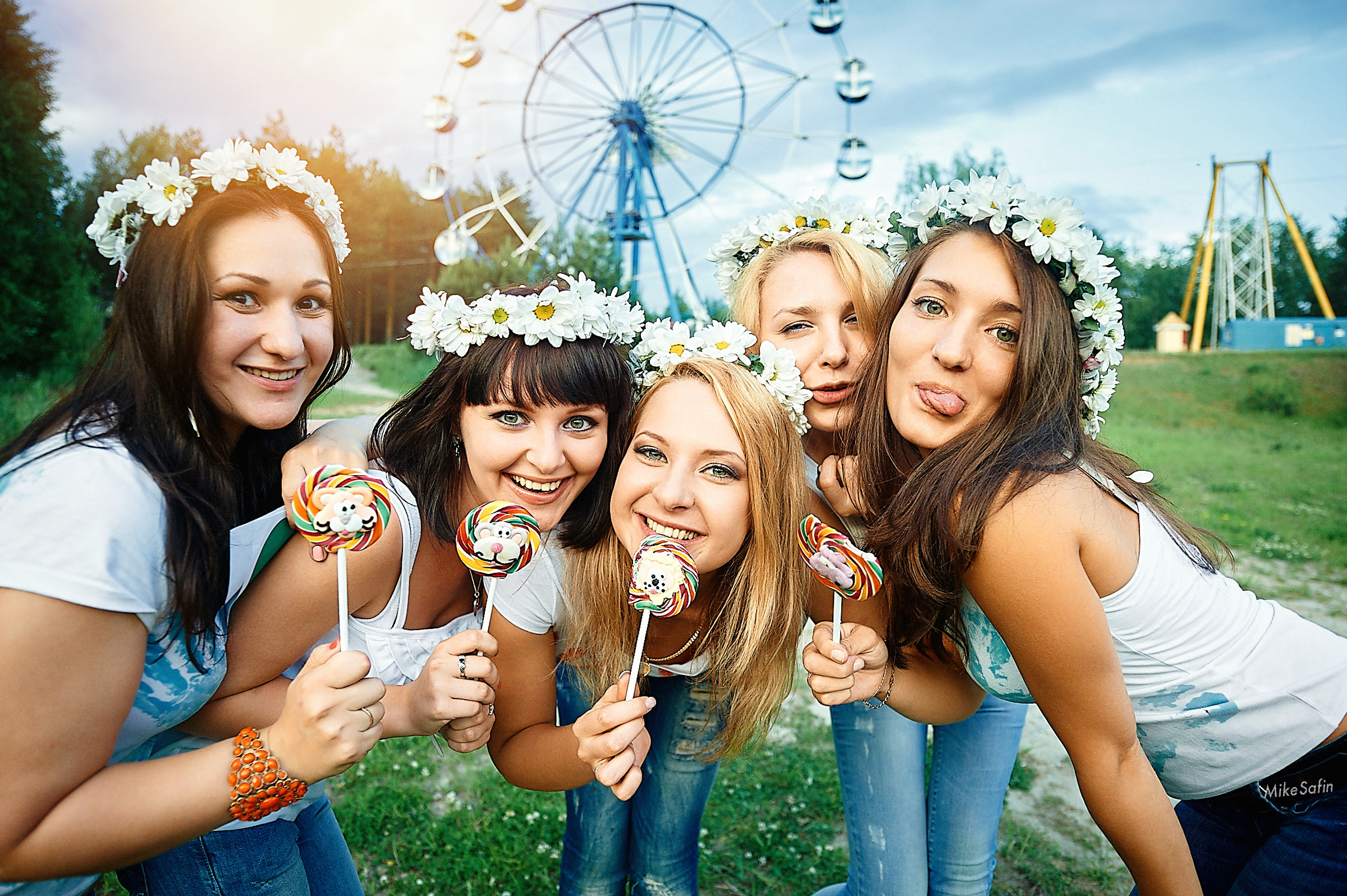 Групповая фотография девушек с венками на голове, в парке на фоне чертового колеса