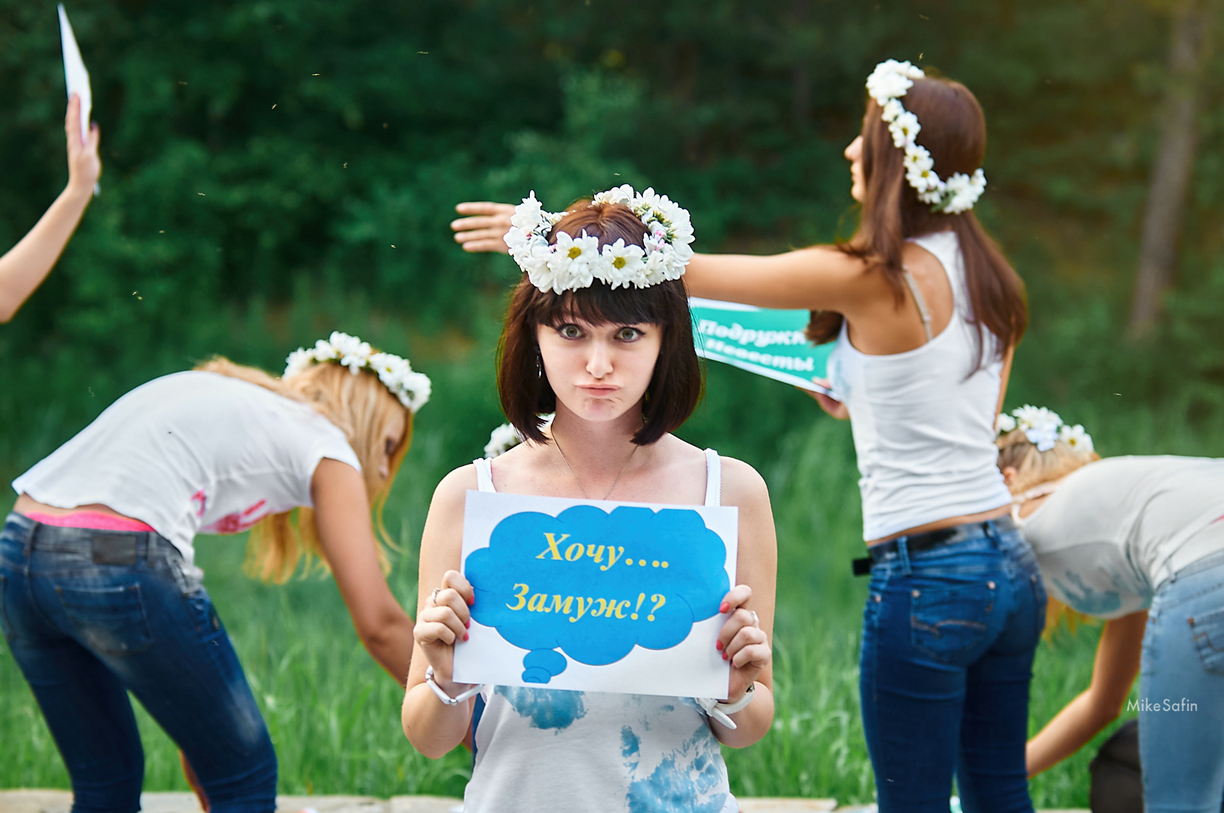 девушка с венком на голове держит табличку с надписью