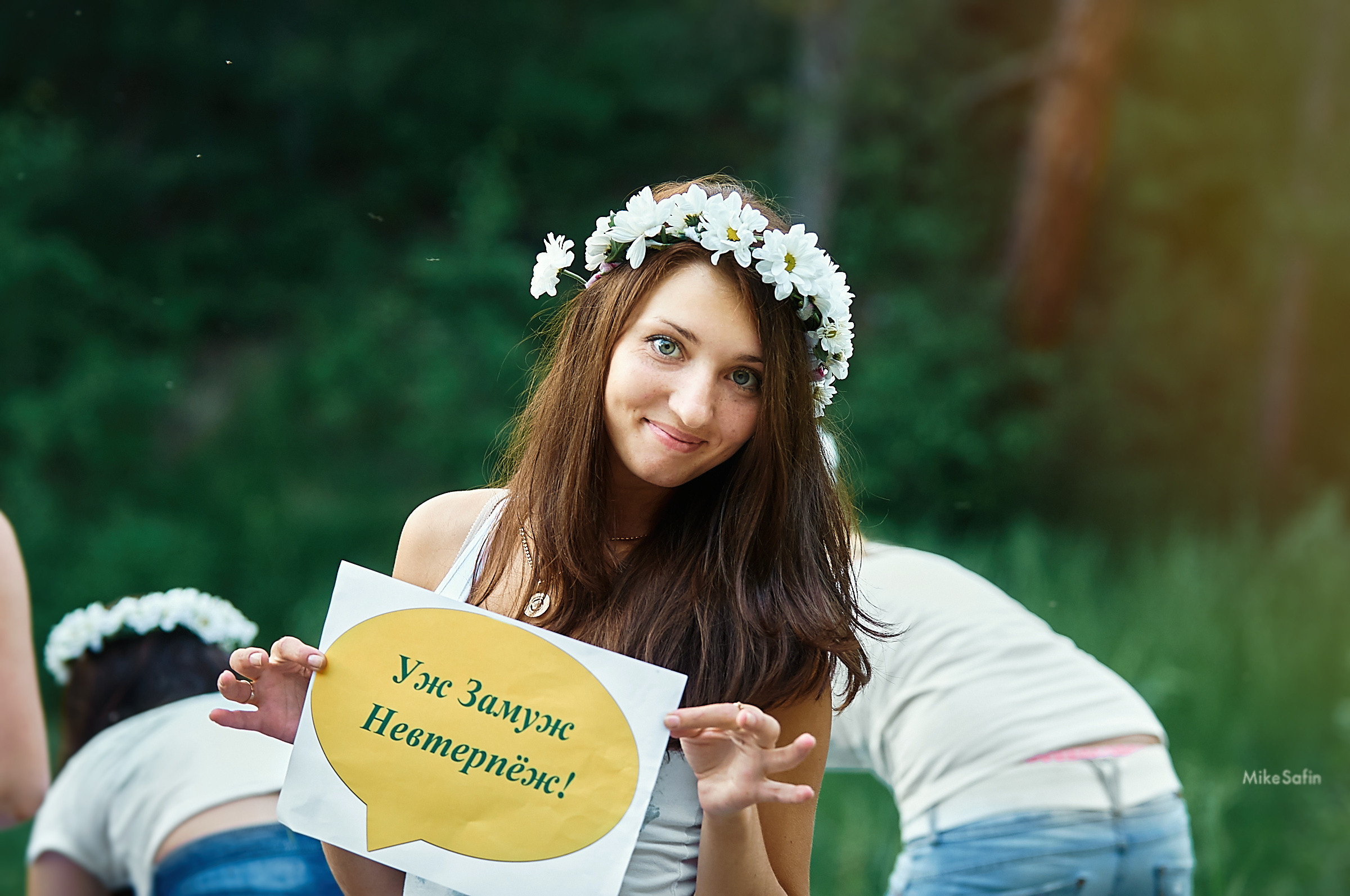 скромная подруга невесты с венком на голове держит табличку с надписью