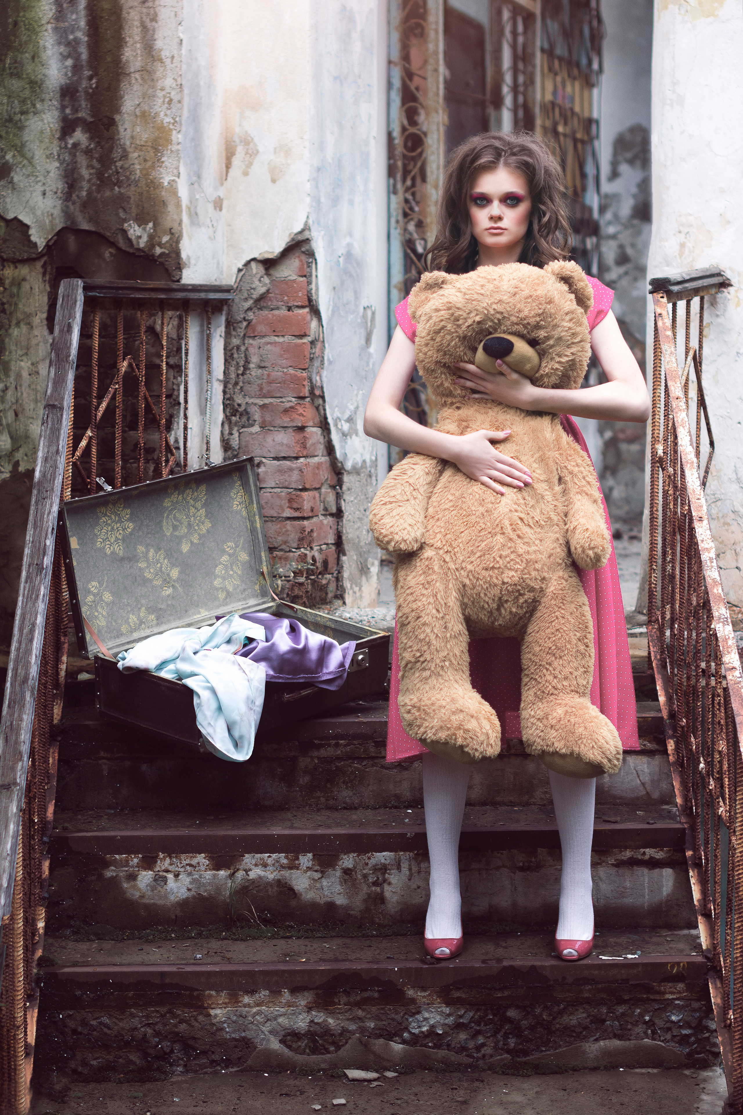 Девушка с большим плюшевым медведем на крыльце старого дома