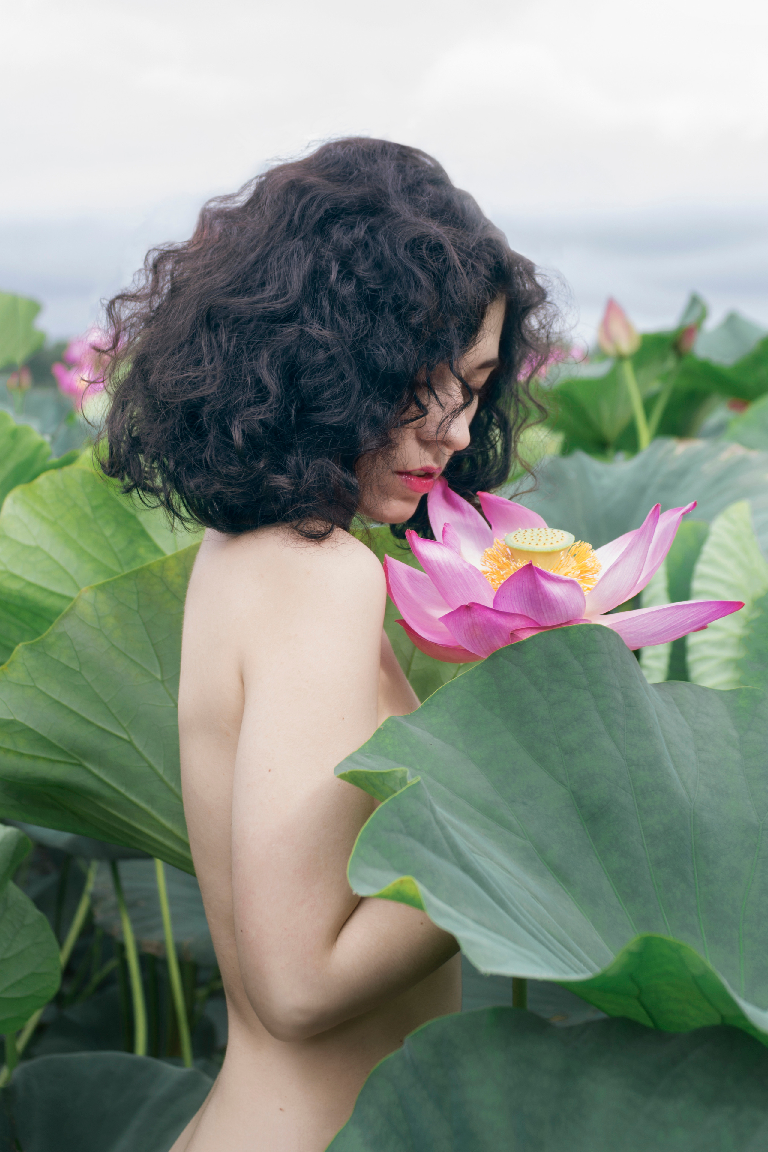Раздетая девушка в цветах лотоса, вид в профиль