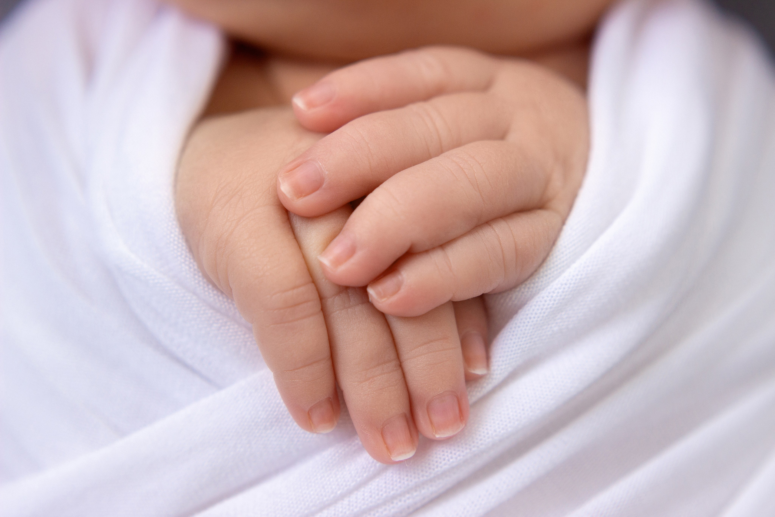 краснодар, высунутые ручки новорожденного мальчика с коликами беспокойным животиком в бело-серых тонах, после успокоения, укатанного в обмотку