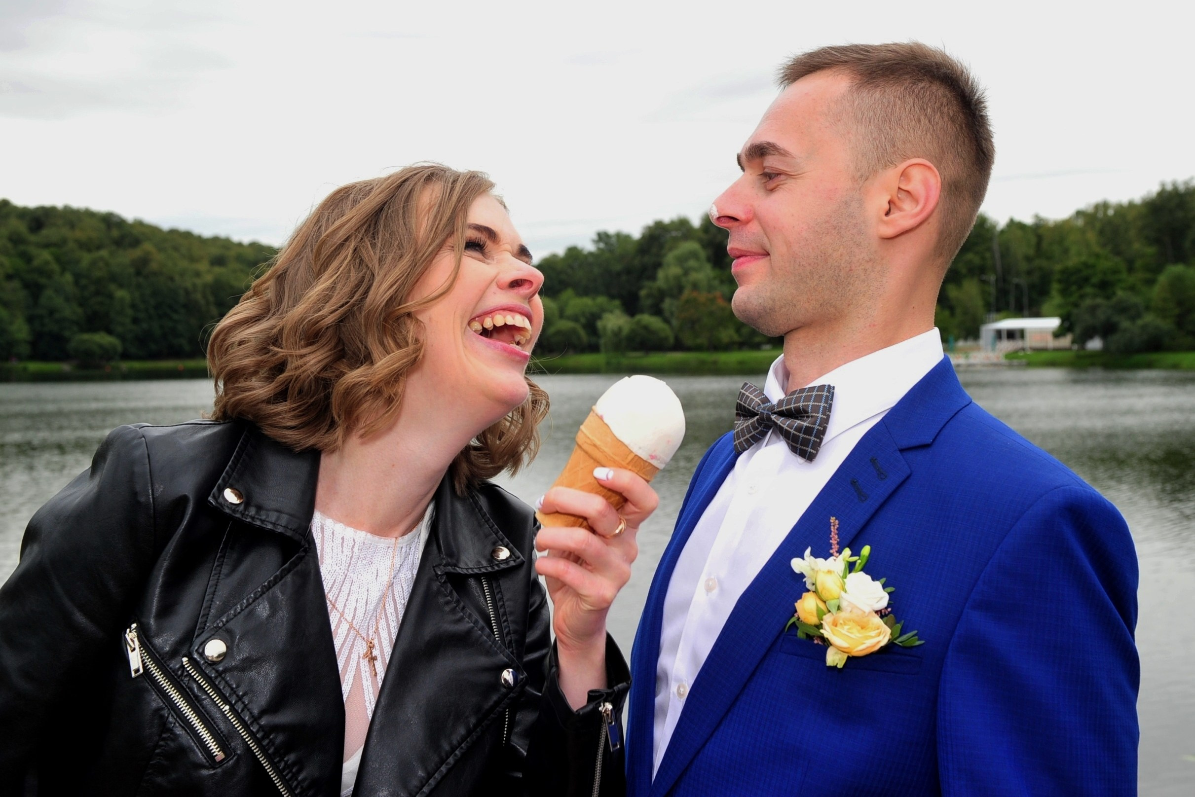 Свадьба в Царицыно хмурым прохладным летним днём, весёлая невеста предлагает жениху мороженое в вафельном стаканчике