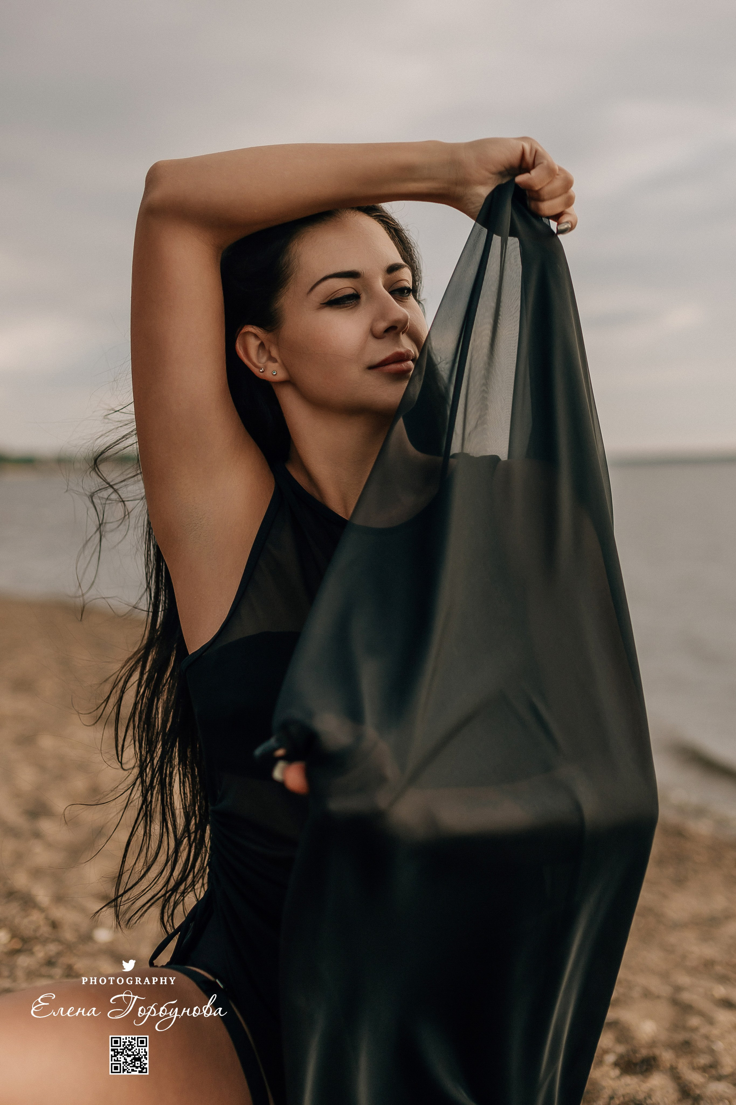 Фотосессия с черной тканью. Легкая черная вуаль летит на вертру. Фотосессия у реки черная серия с тканью. Девушка укуталась в черную ткань. Прогулка по набережной. Песок, речка, модель в черном. Качели над водой, Закат. Девушка лежит на песке. В зеленых деревьях
