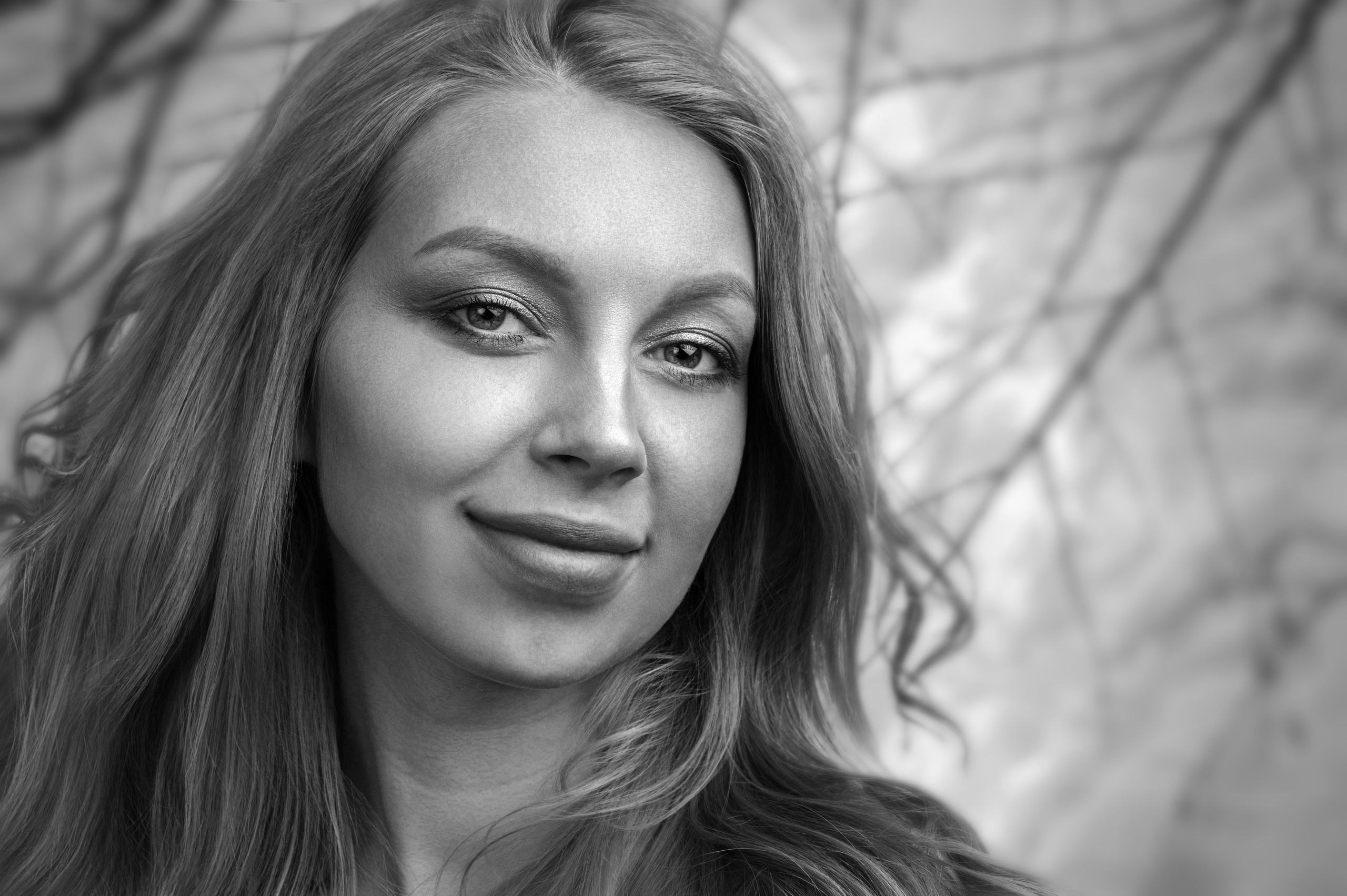 Девушка со светлыми вьющимися волосами на фоне из веток