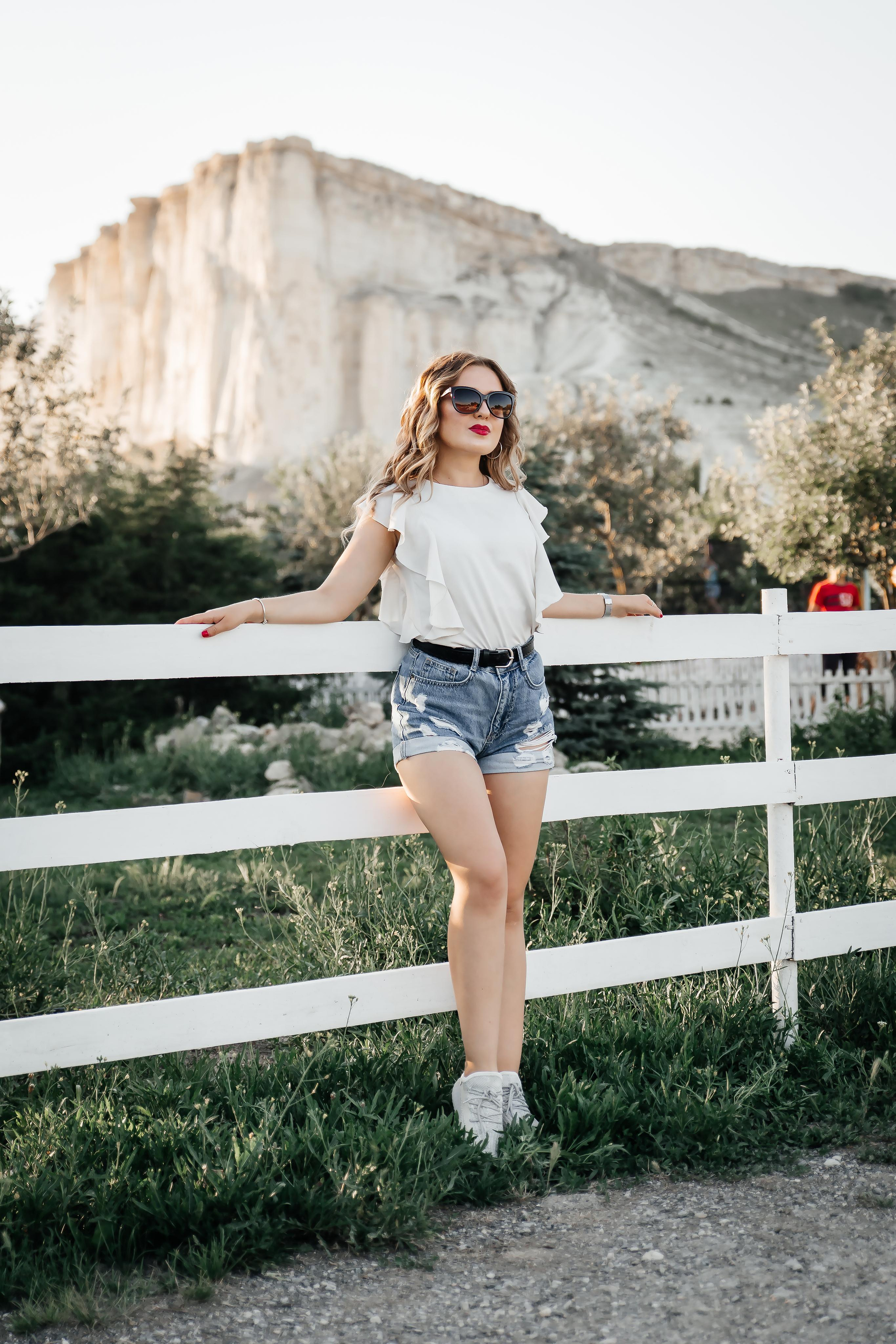 Девушка стоит на фоне скалы.