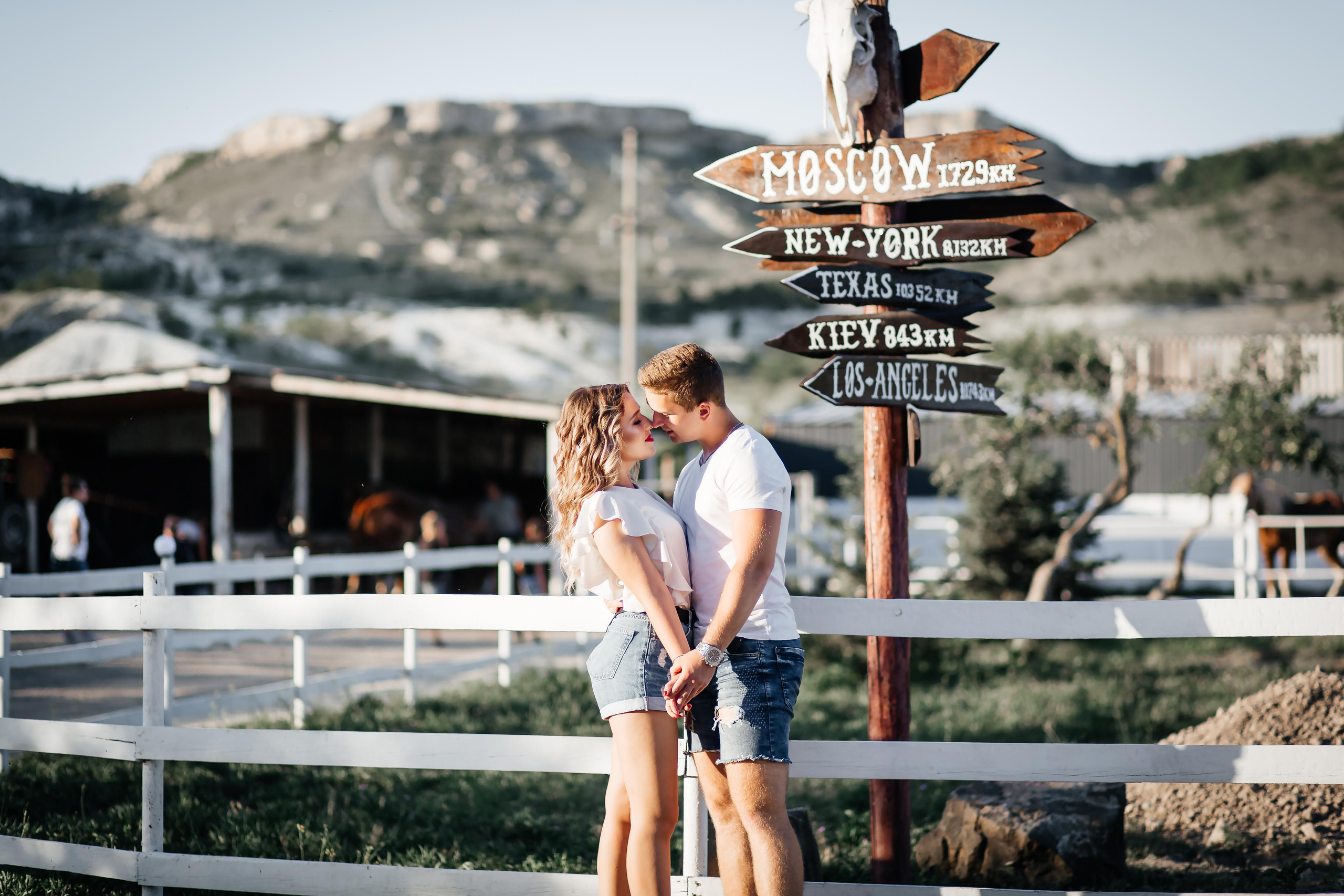 Пара обнимается на фоне красивого указателя дорог.
