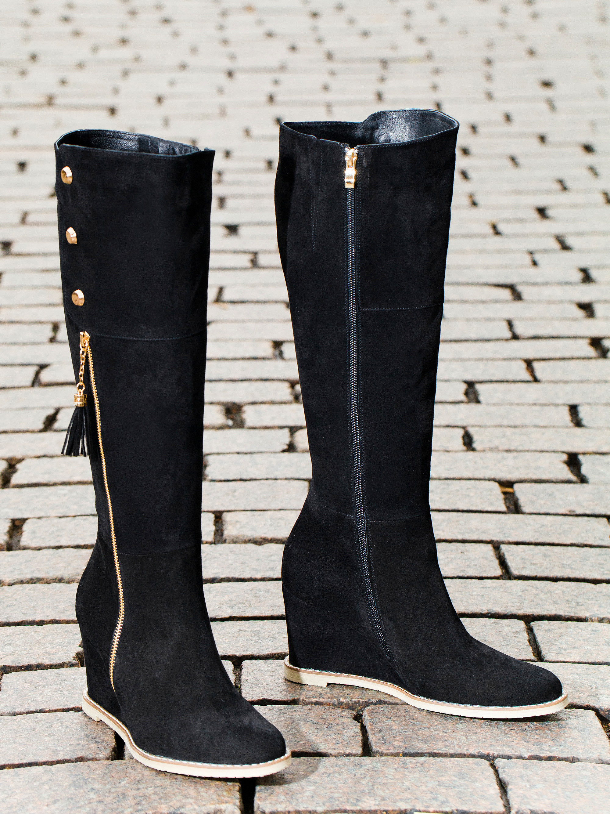 Художественная съемка сапогов на танкетке с белой подошвой на фоне улицы.