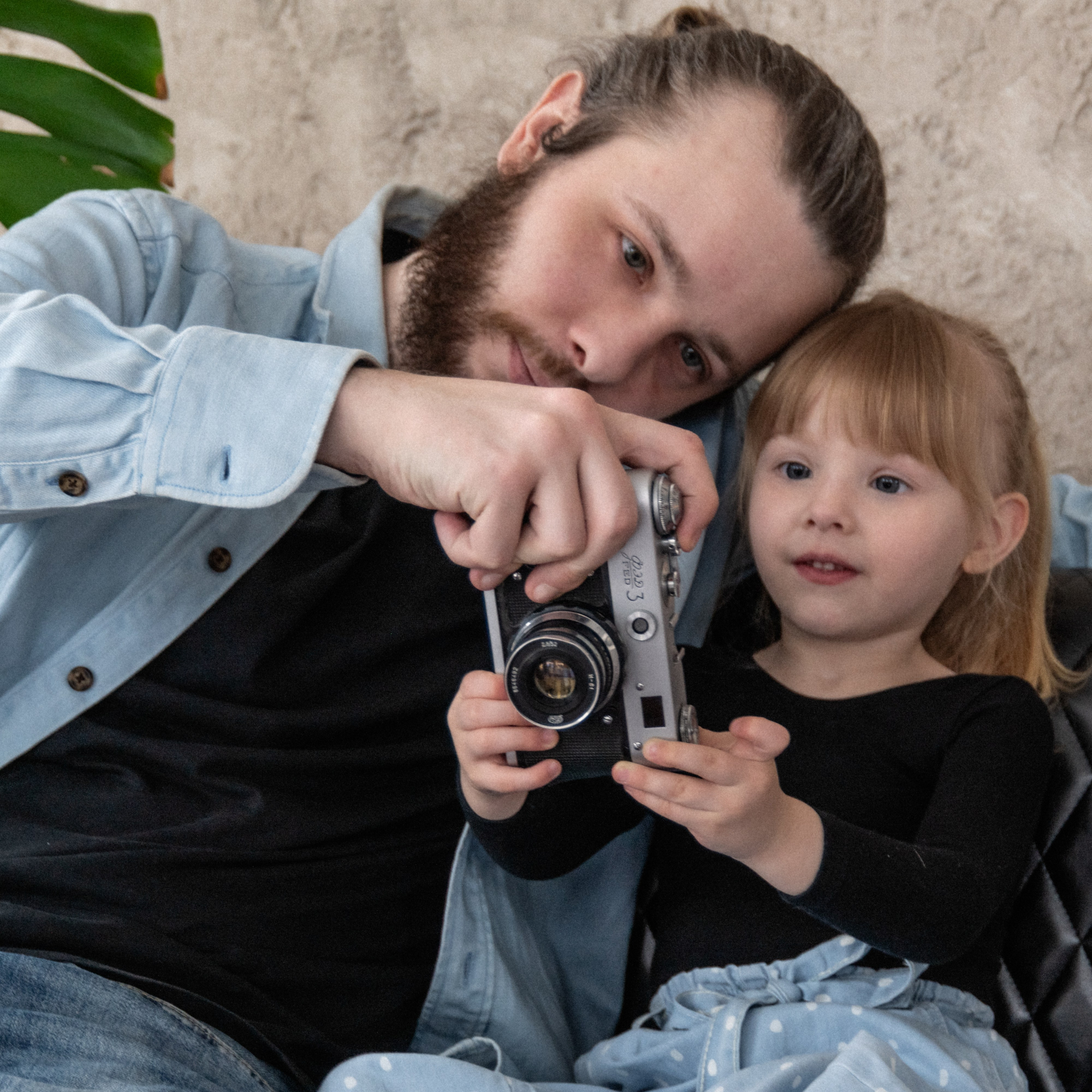 Папа обучает маленькую дочь пользоваться камерой — момент внимания, тепла и семейной связи на фотографии.