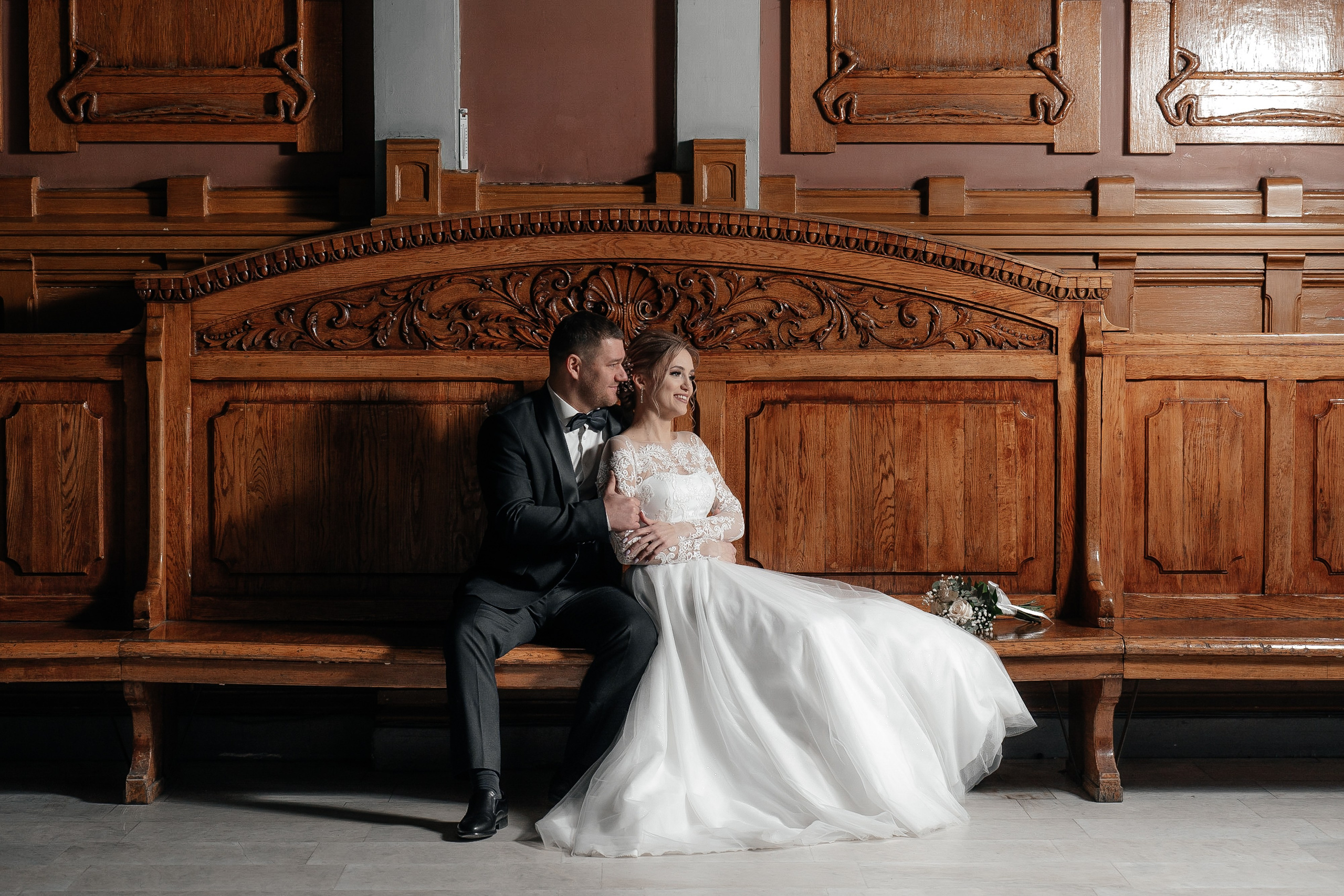 Свадебная фотосессия невесты и жениха на Витебском вокзале в зале ожидания на большой деревянной скамейке