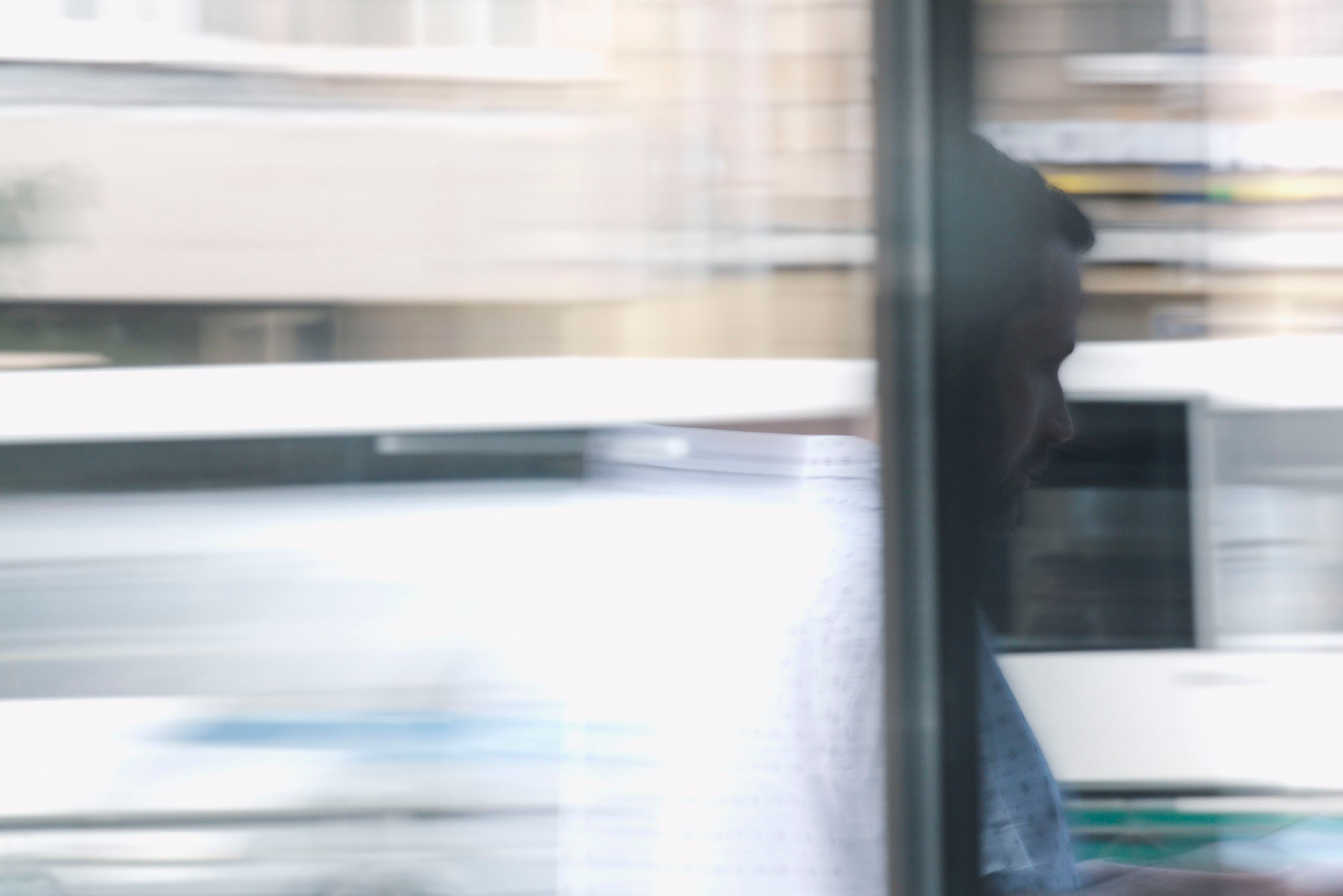 Размытое изображение движения: силуэт мужчины виден сквозь окно.