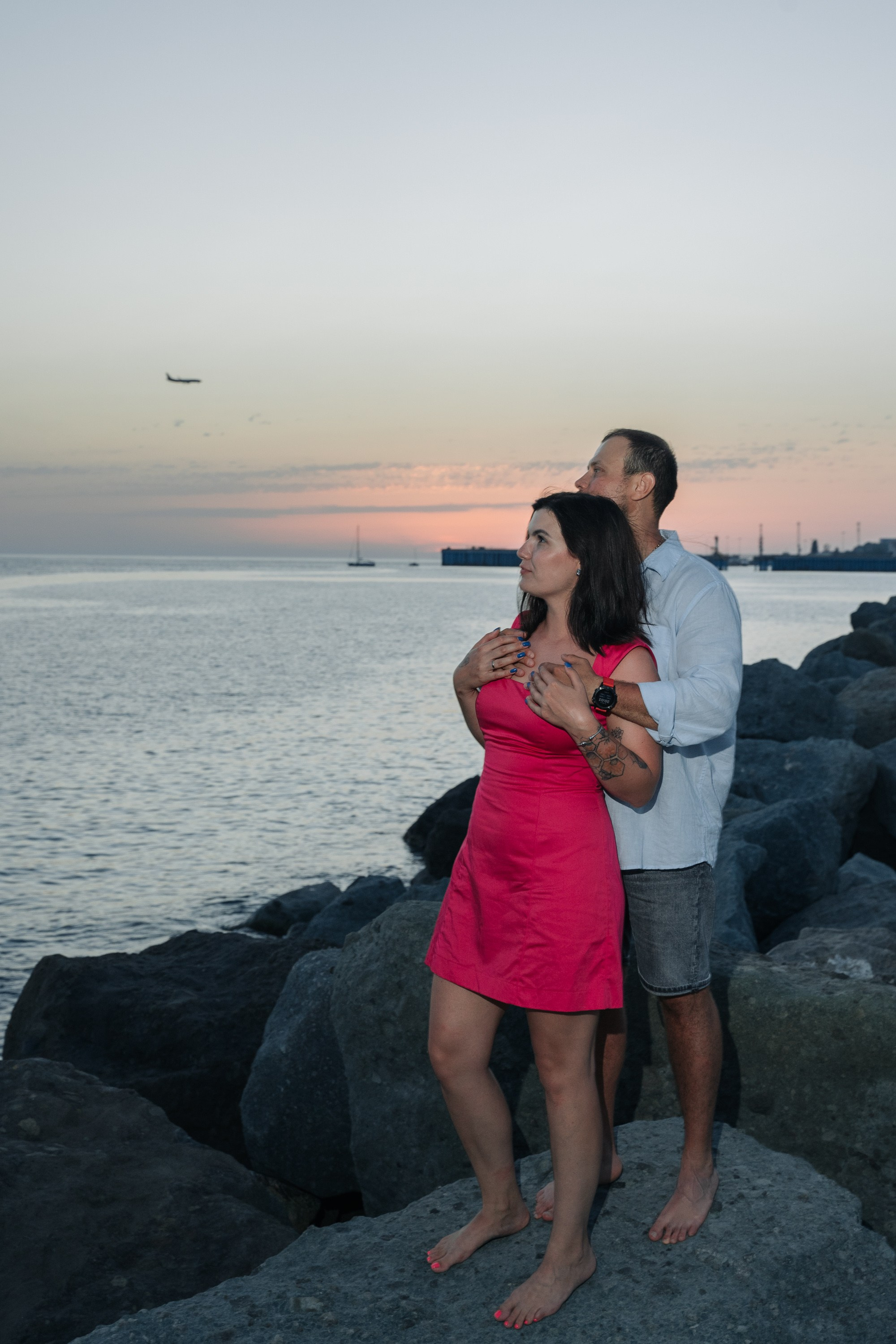 Снимок в полный рост девушки и парня на фоне закатного моря