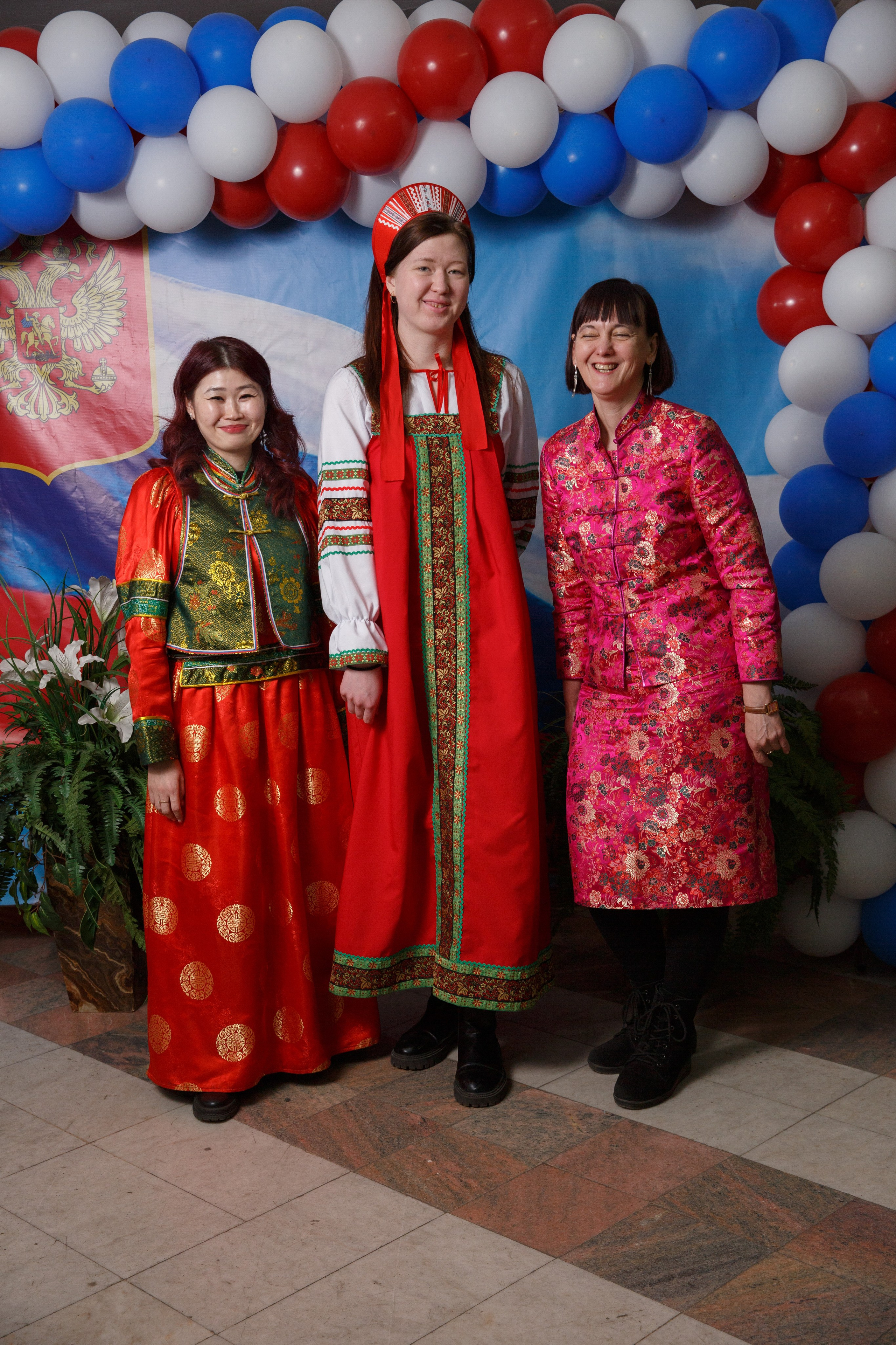 Сотрудники в национальной одежде позируют у декора из шаров.