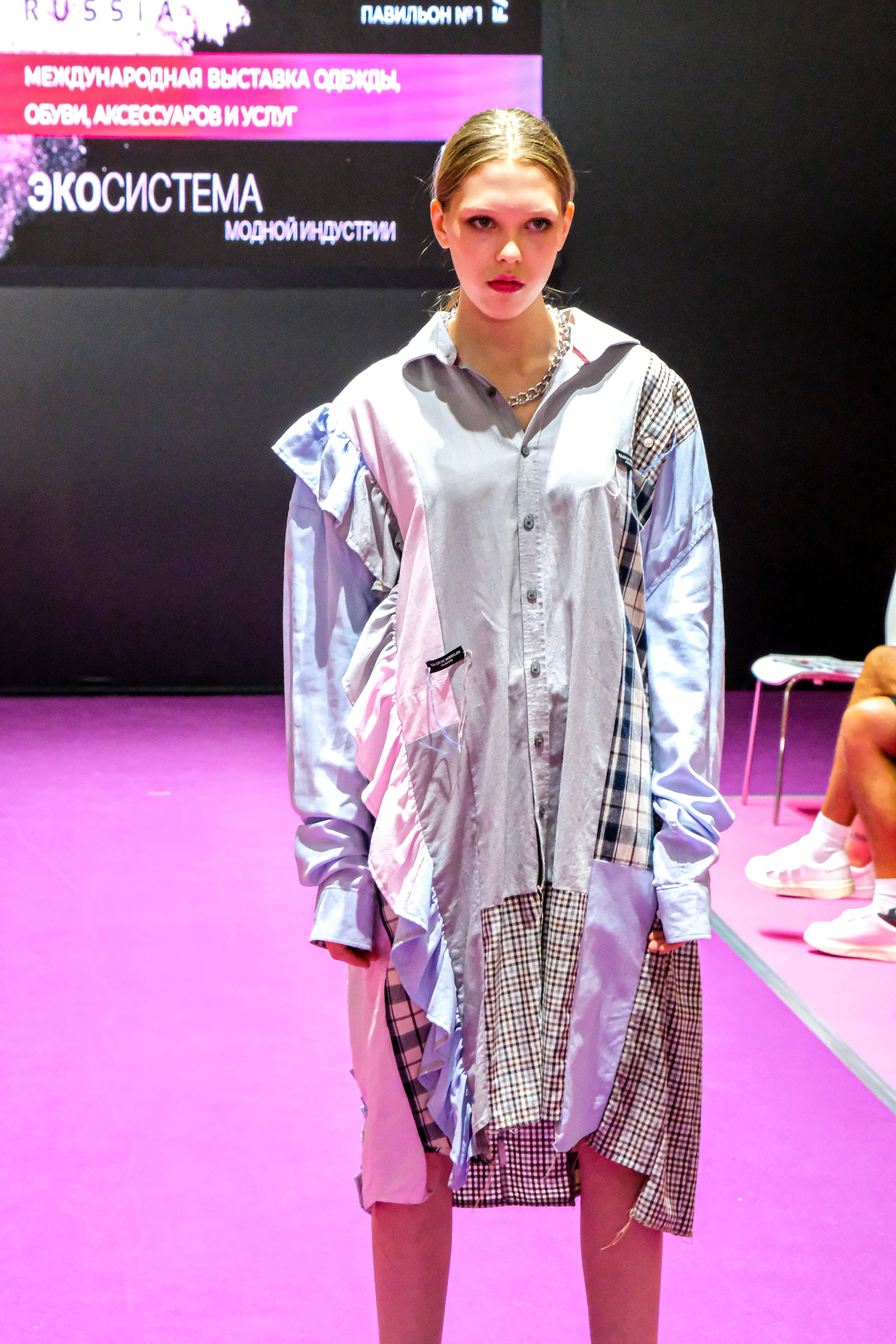  "Модели в ярких нарядах проходят по подиуму во время показа мод, освещенные яркими софитами и окруженные восторженными зрителями."