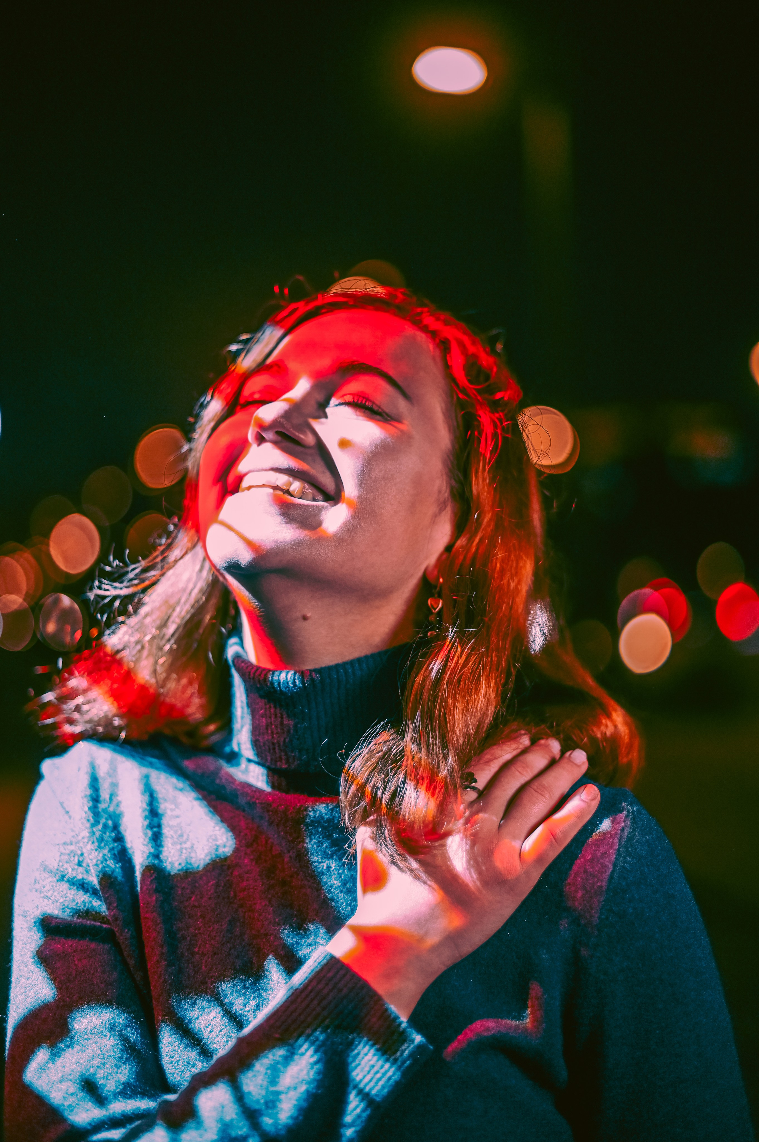 Ночной портрет улыбающейся девушки с волнистыми рыжими волосами, снятый в Москве с эффектными городскими огнями.