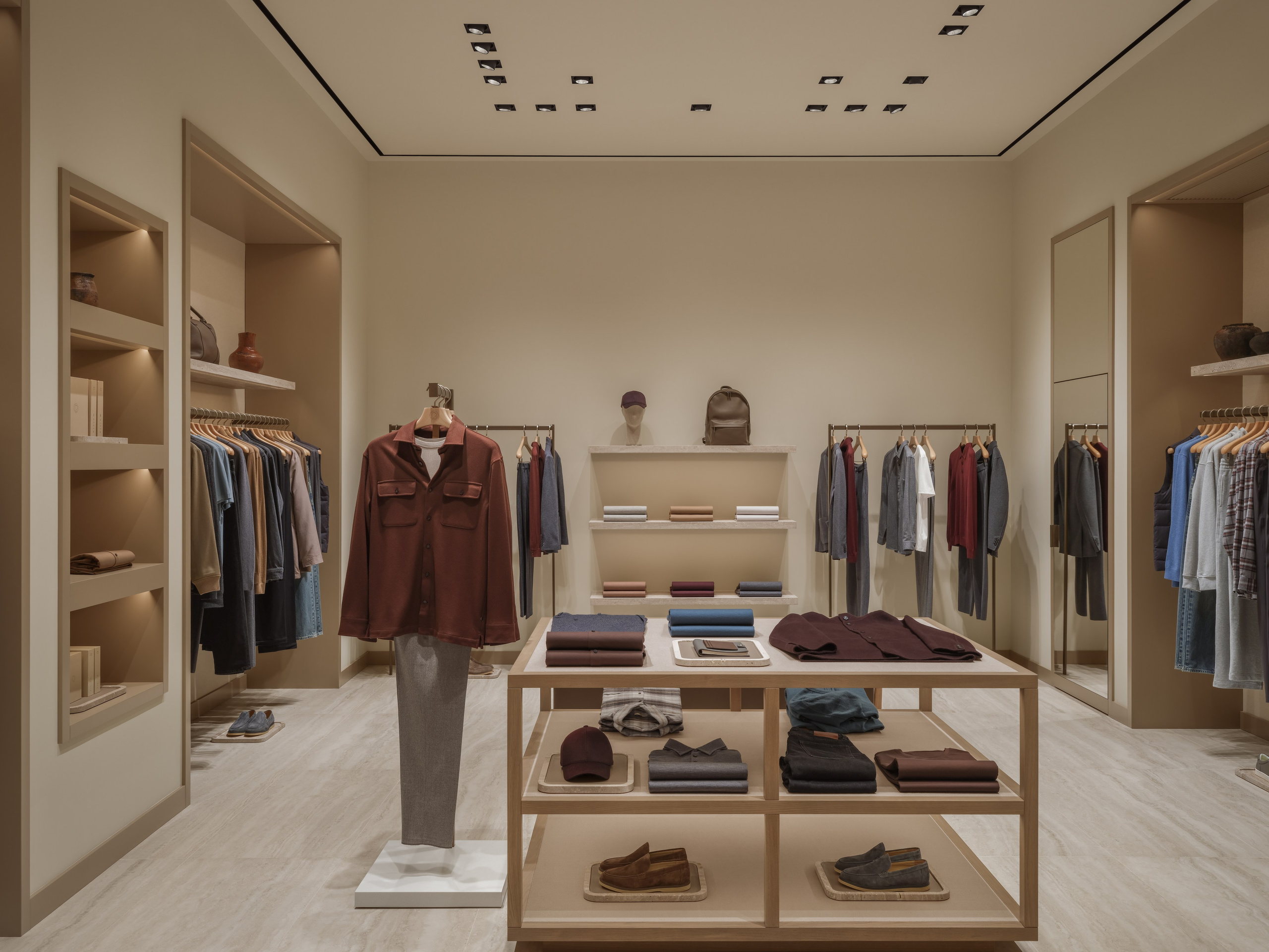 Symmetrical interior photograph of the 12 STOREEZ fashion boutique in Astana, emphasizing minimalist retail architecture, display tables and merchandising composition.