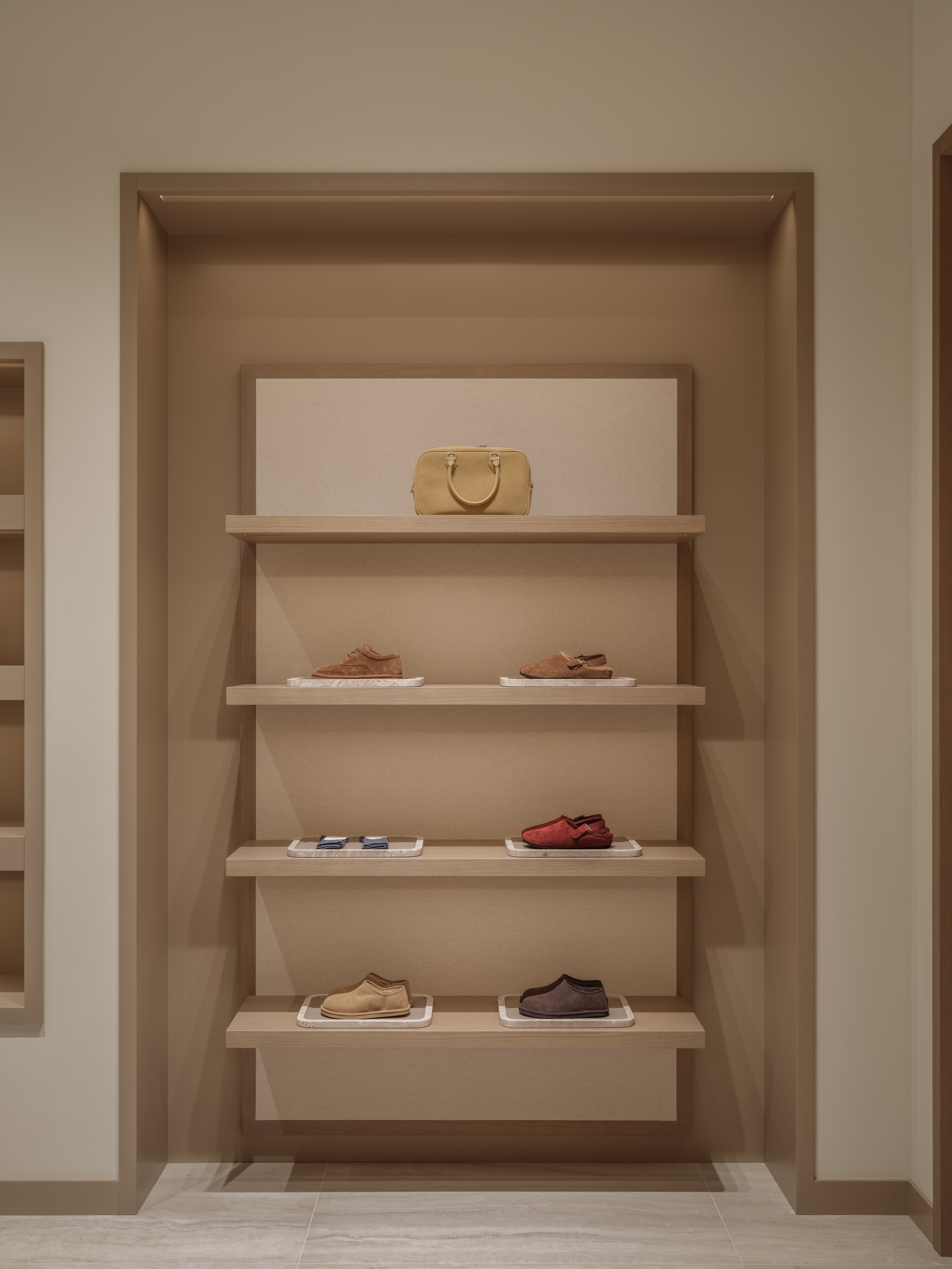 Custom retail shelving displaying footwear and accessories inside the 12 STOREEZ boutique in Astana, photographed to highlight minimalist interior design and luxury merchandising.
