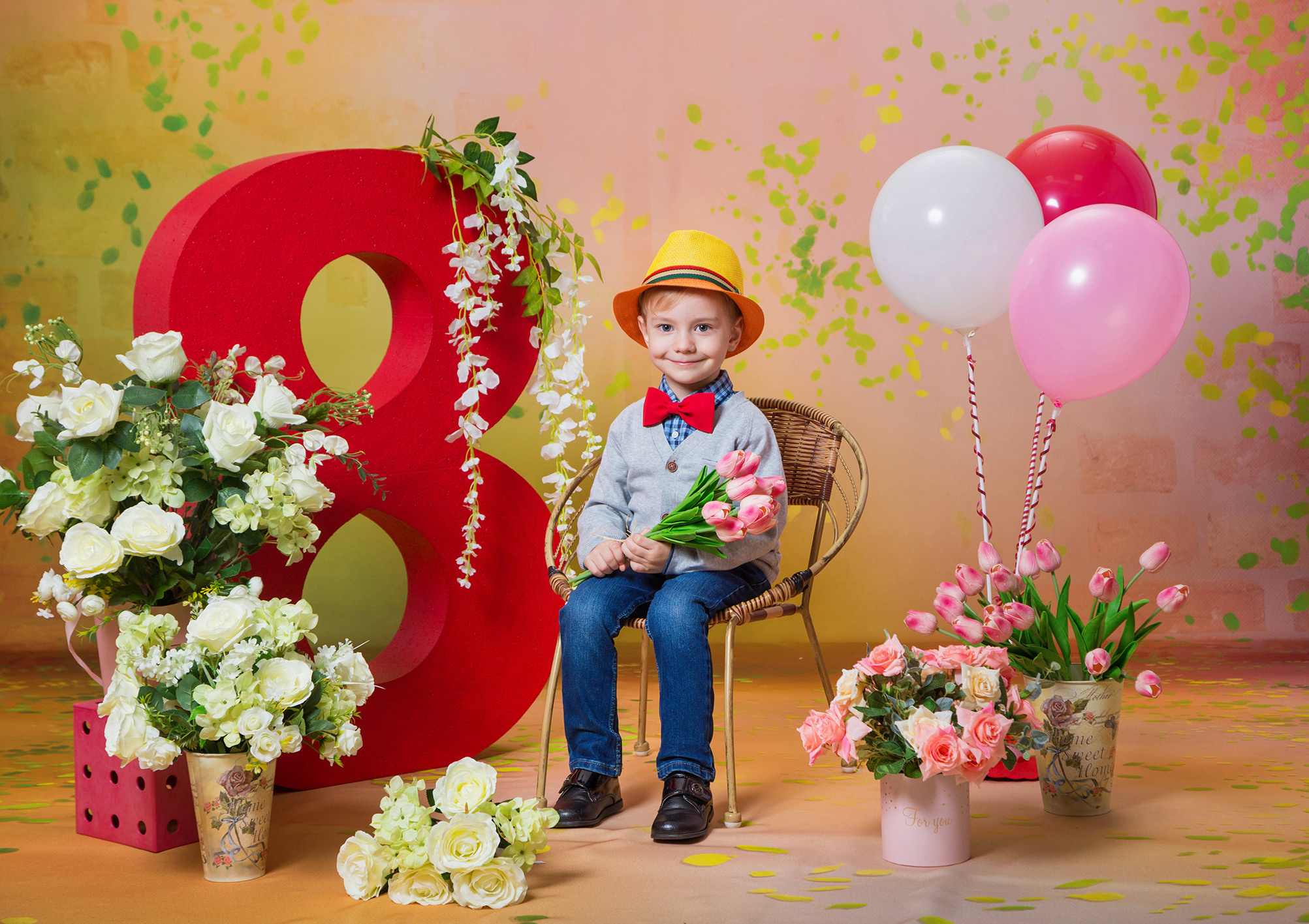 Костюмированная выездная фотосессия для детского сада к 8 марта. Мальчик в желтой шляпе, с красной бабочкой и цветами.