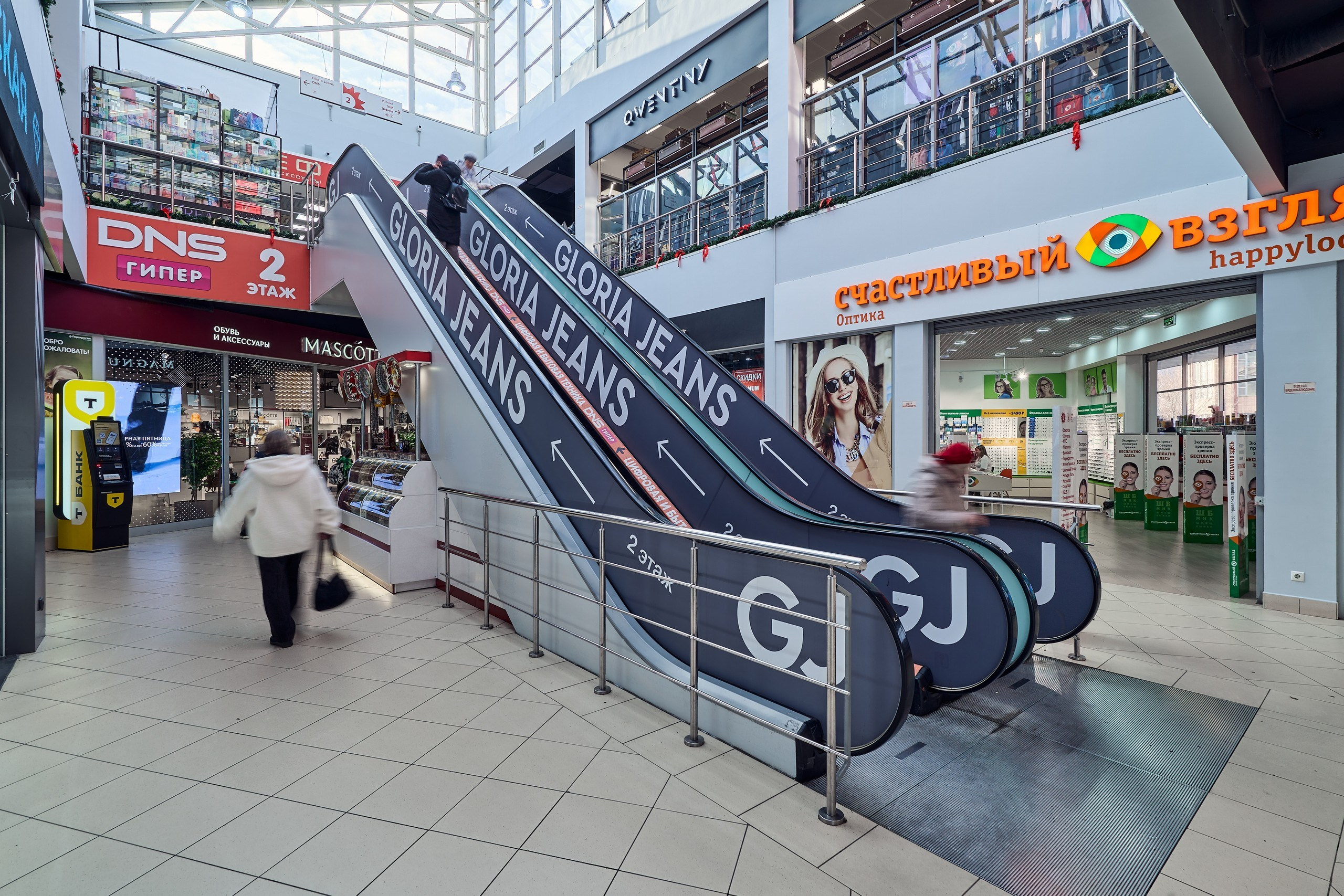 Интерьерная фотосъемка центральной части торгового центра в г. Раменское с видом на эскалаторы, естественным светом и павильонами нескольких арендаторов
