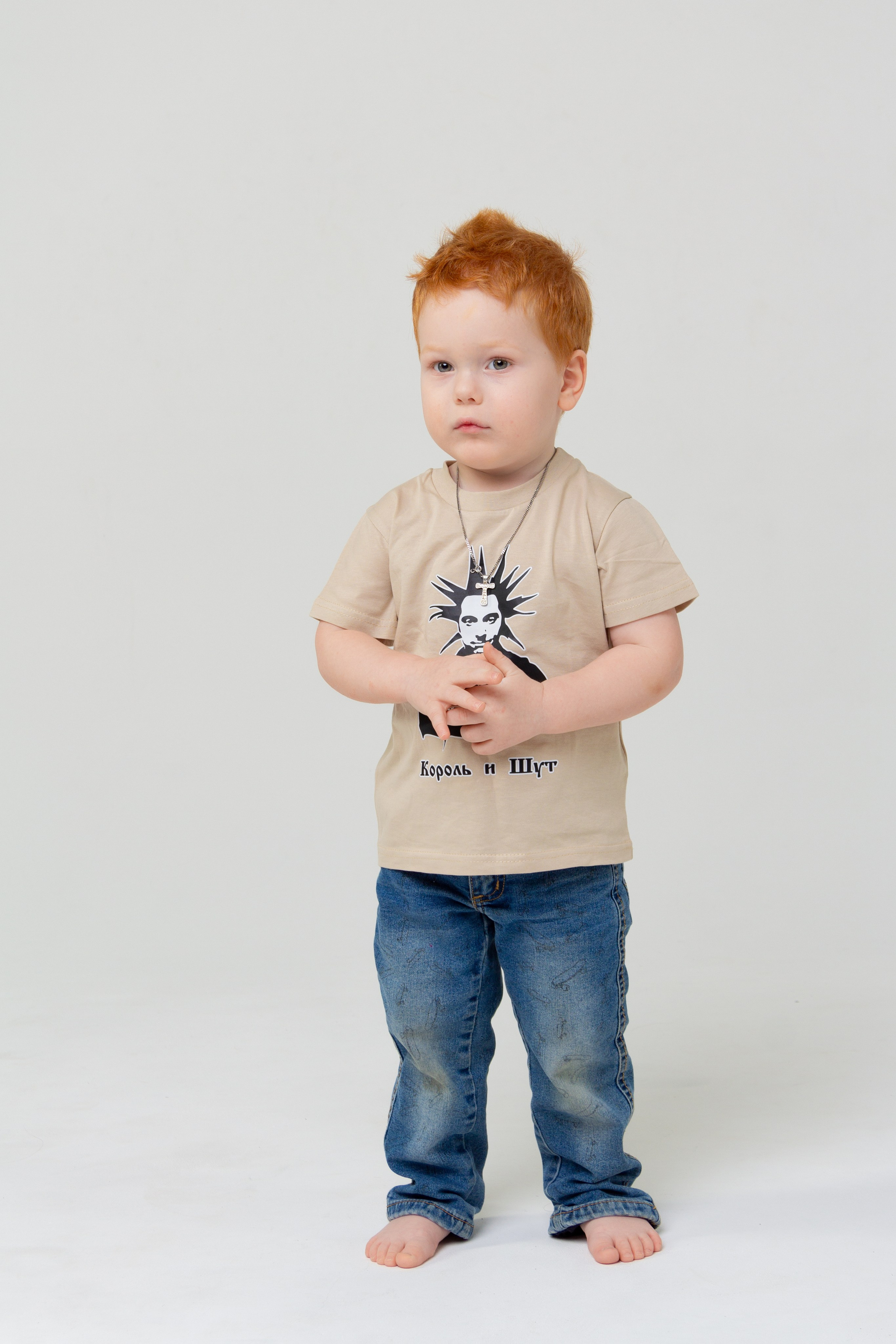 Рыжеволосы мальчик в джинсах и футболке на фотосессии  в циклораме 