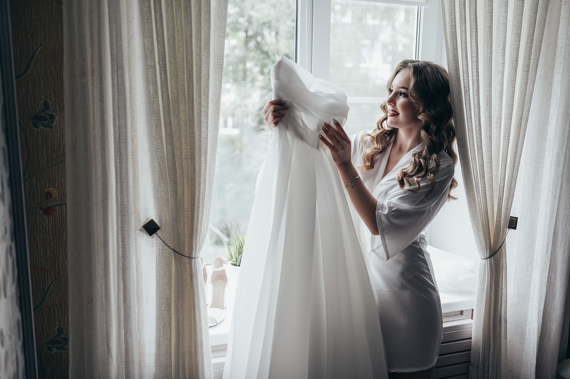 невеста с платьем невесты у окна 