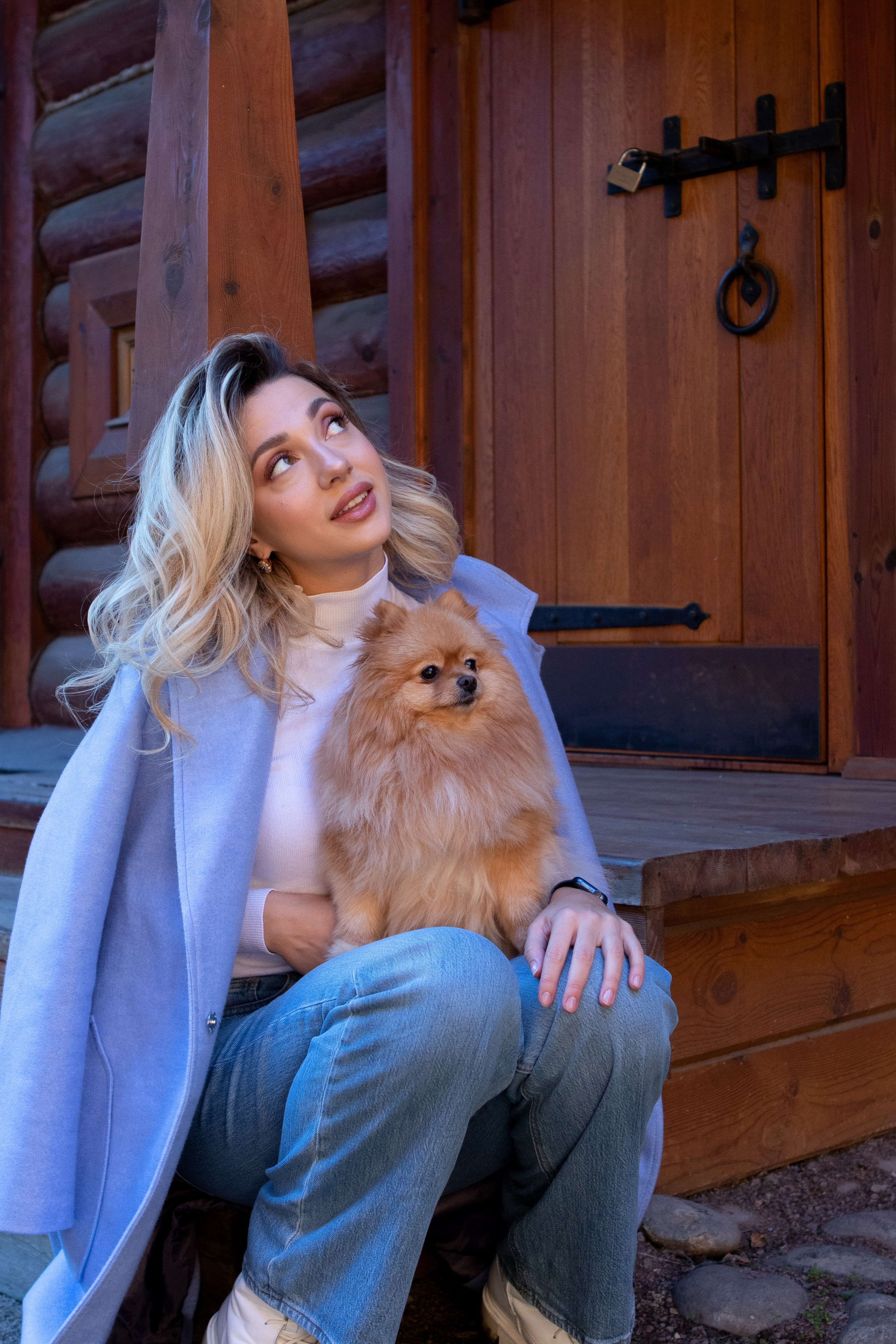 девушка сидит на ступеньках со своей собакой шпицем на коленях