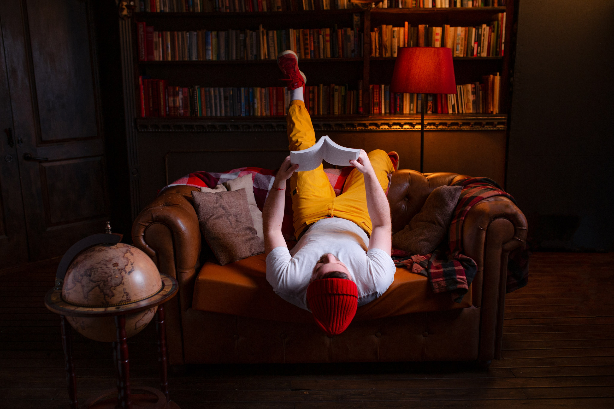 Парень необычно читает книгу вниз головой. 