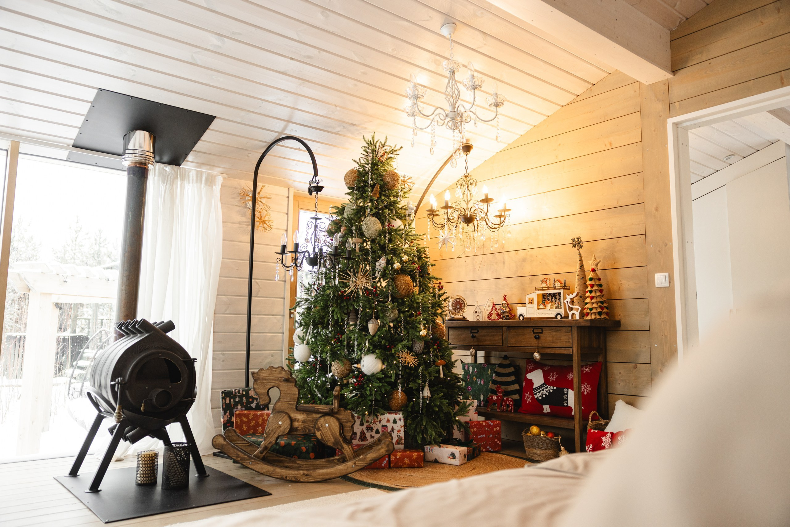 Интерьер загородного дома 'Панорама': просторная гостиная с большой зелёной ёлкой, сверкающие гирлянды и семейные фотографии