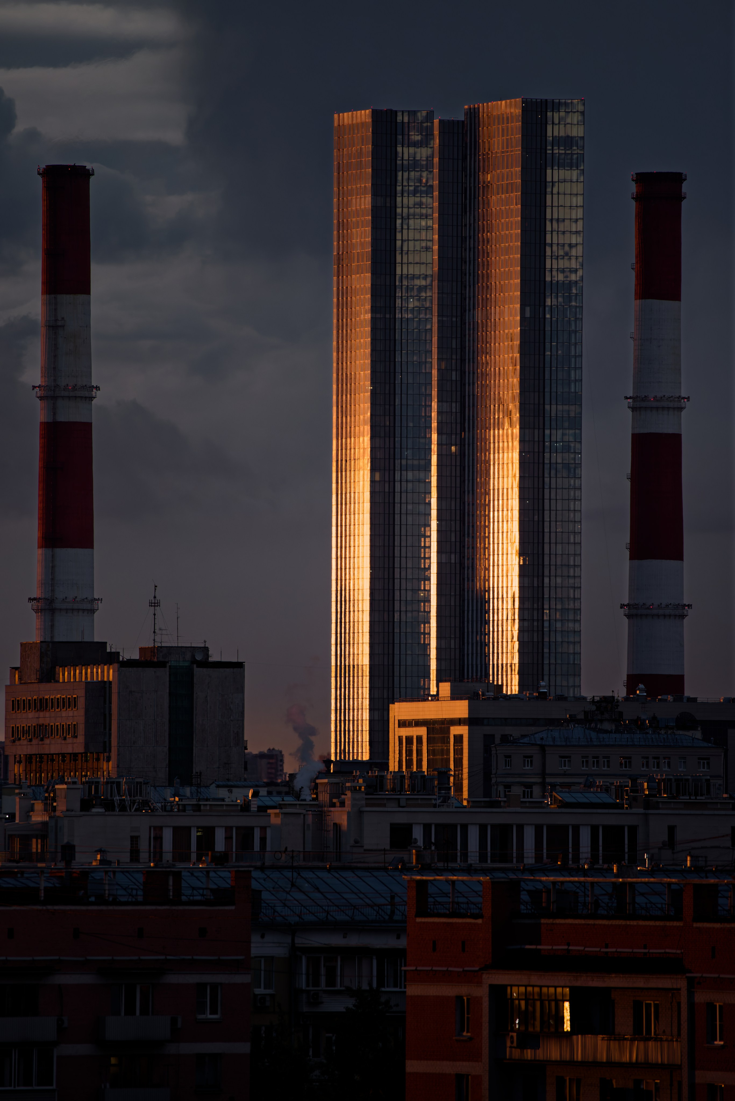 Вид на сияющие в закатных лучах башни Центра Международной Торговли в Москве на фоне серого неба