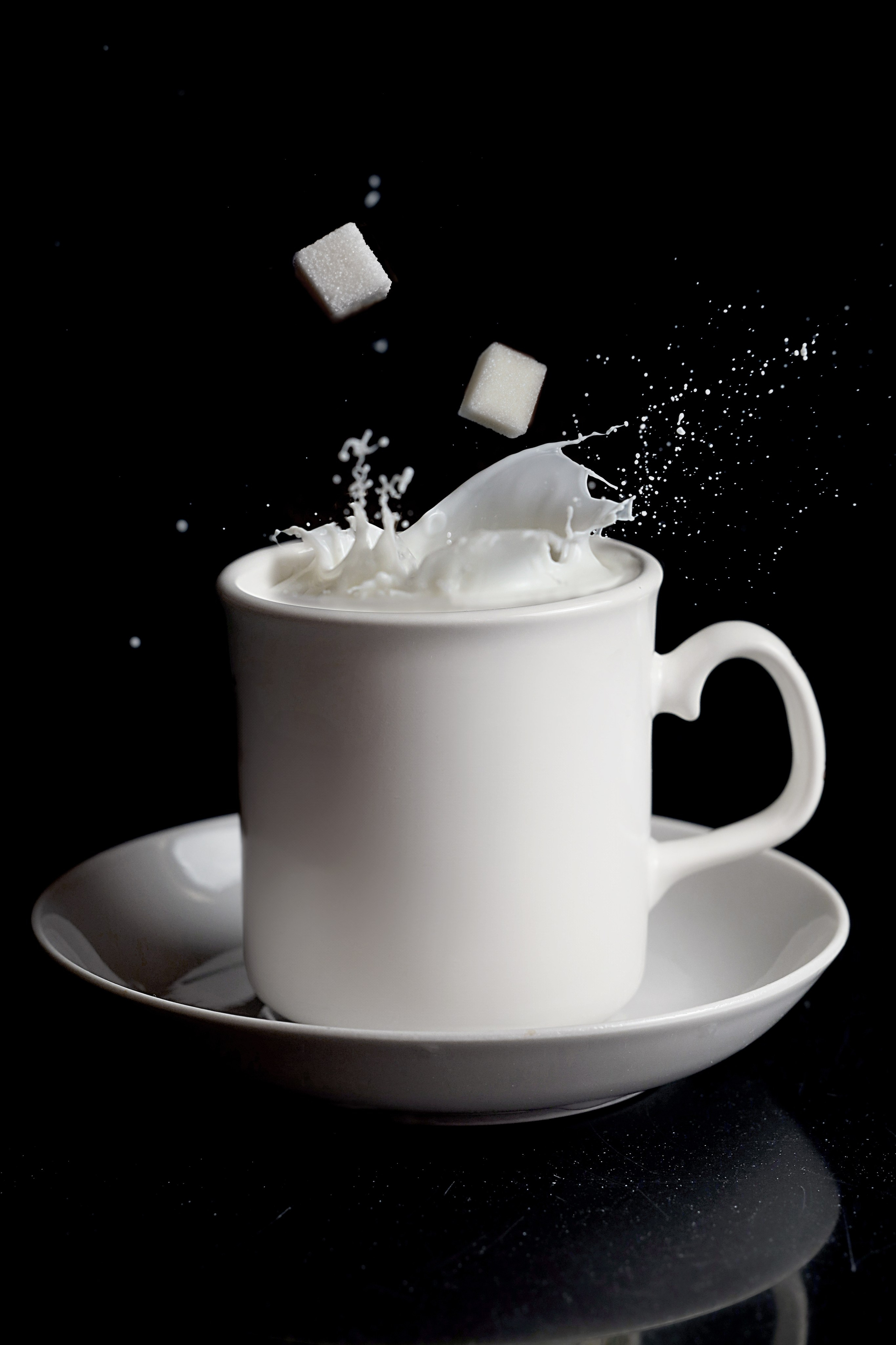 предметная фотосессия белая чашка с молоком и туда падает сахар