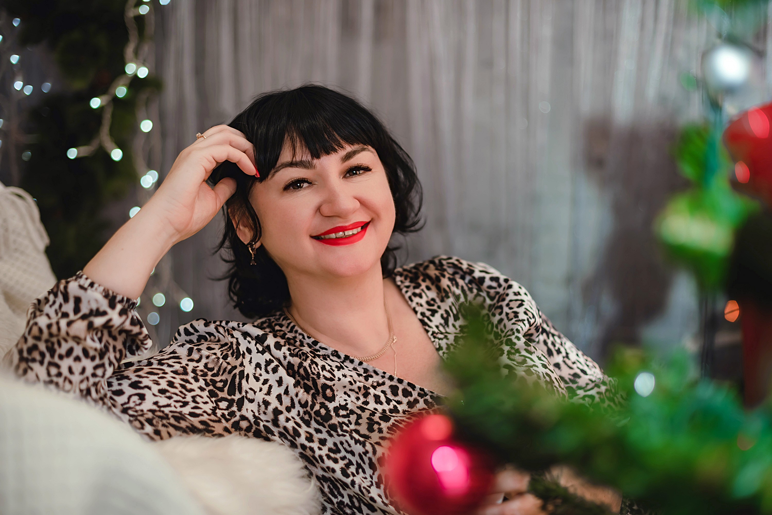 На фото  портрет девушки с подарком сидит около елки.