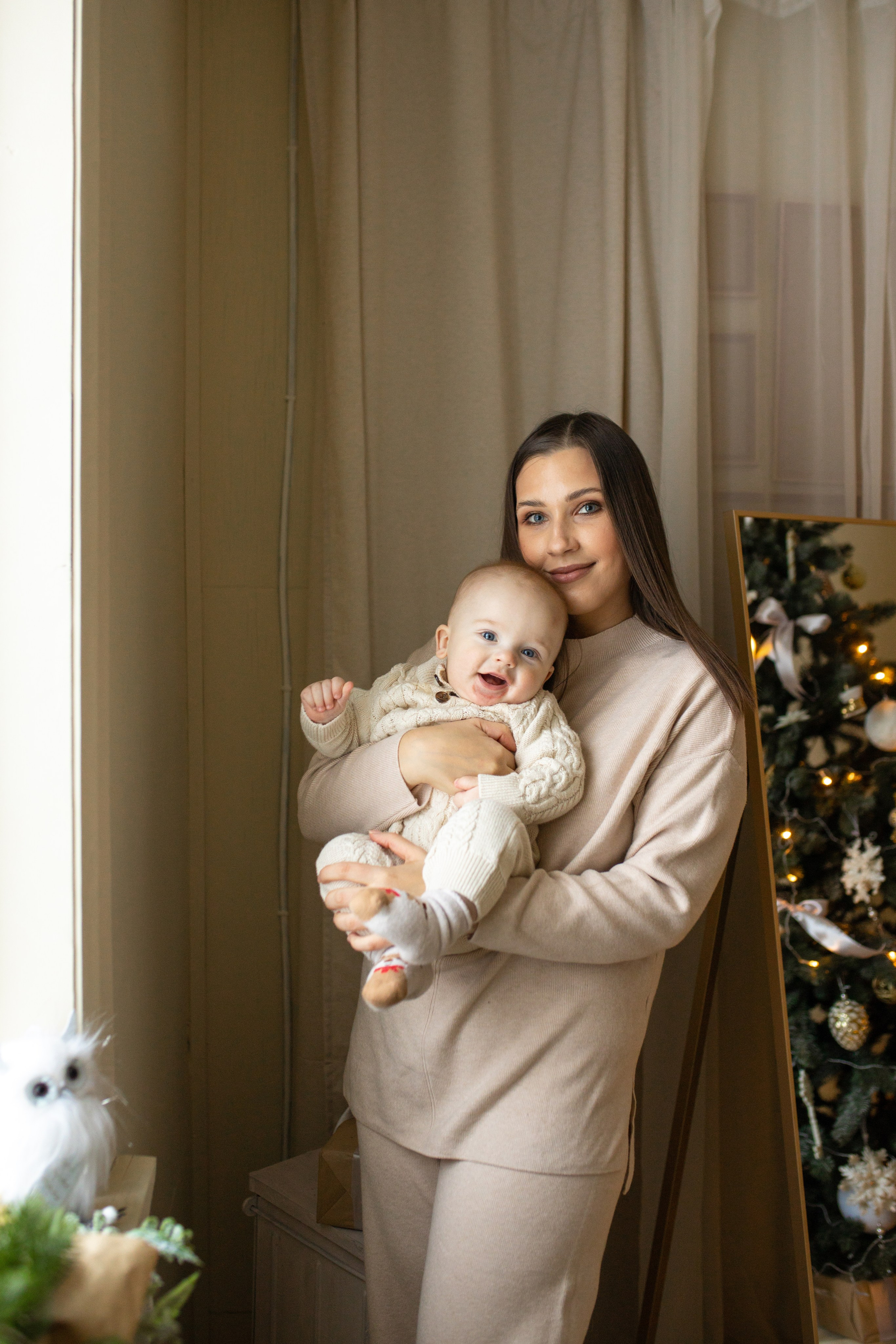 мама с малышом на руках у окна, новогоднее настроение