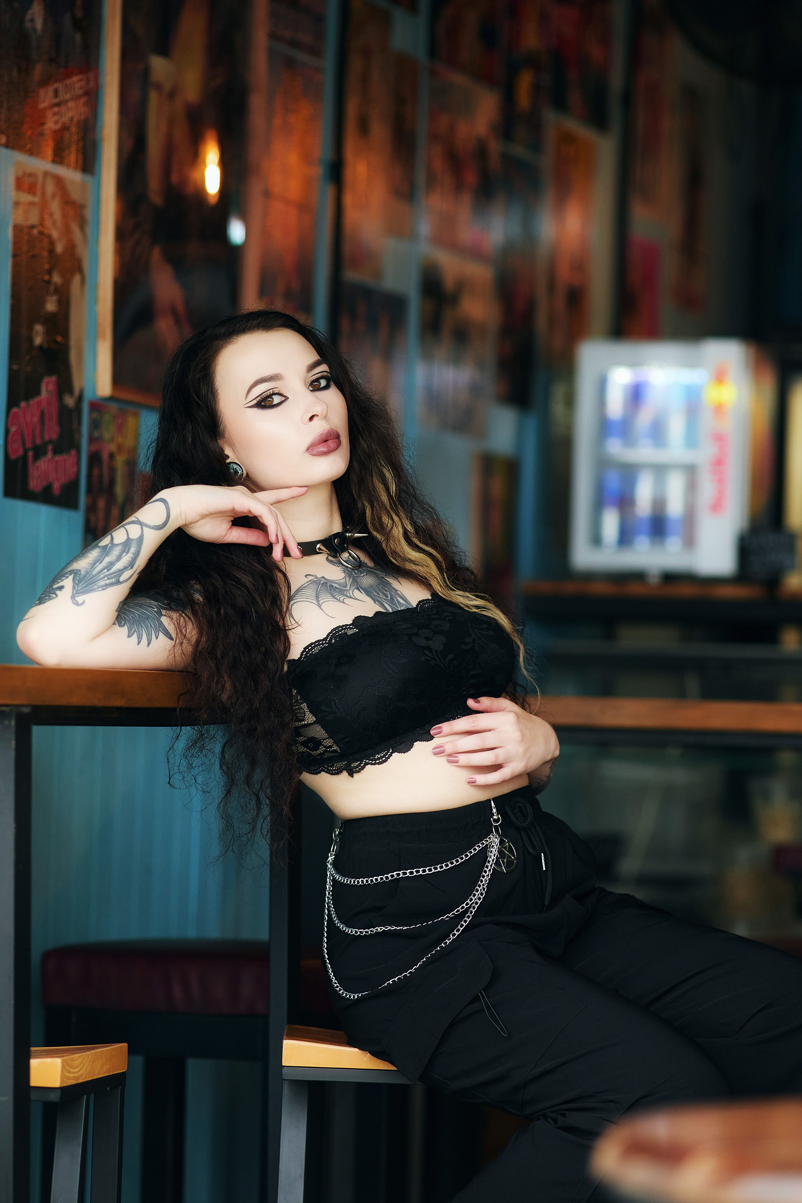 Красивая портретная фотосессия с девушкой в уличном баре. Татуированная модель в чёрном топе позирует на камеру