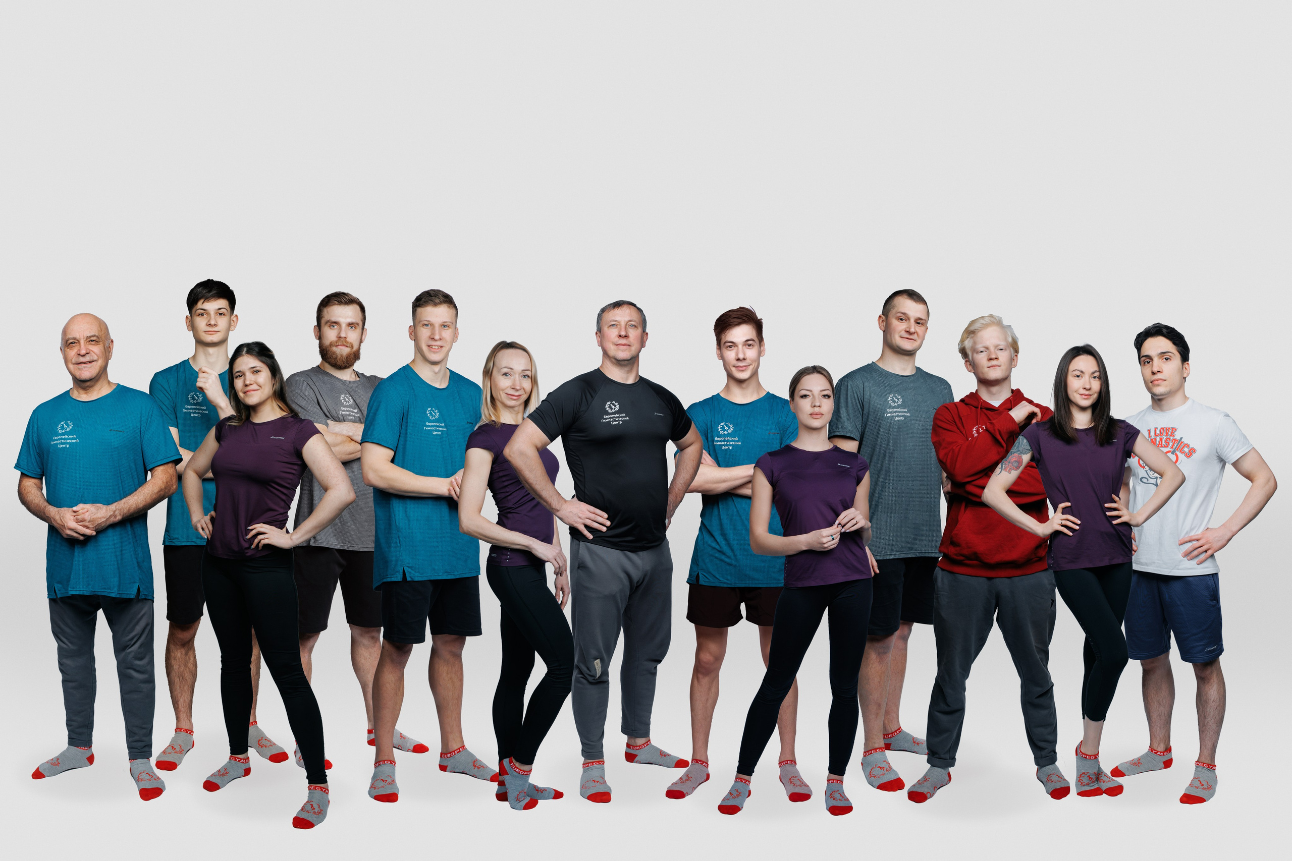 Командное фото спортсменов-гимнастов в форме на студийном фоне.