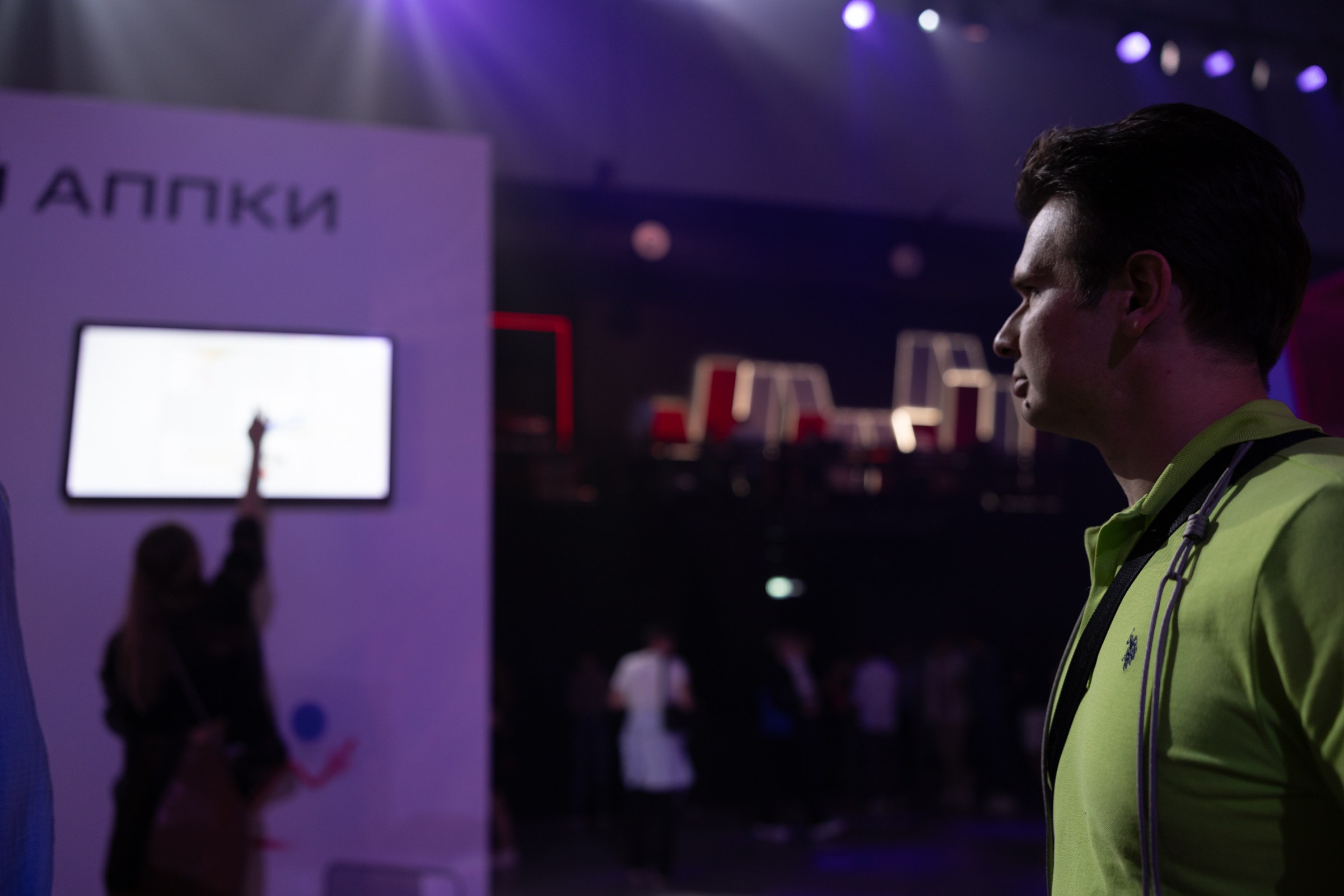 Посетитель взаимодействует с цифровым стендом, репортаж об инновациях и клиентском опыте.