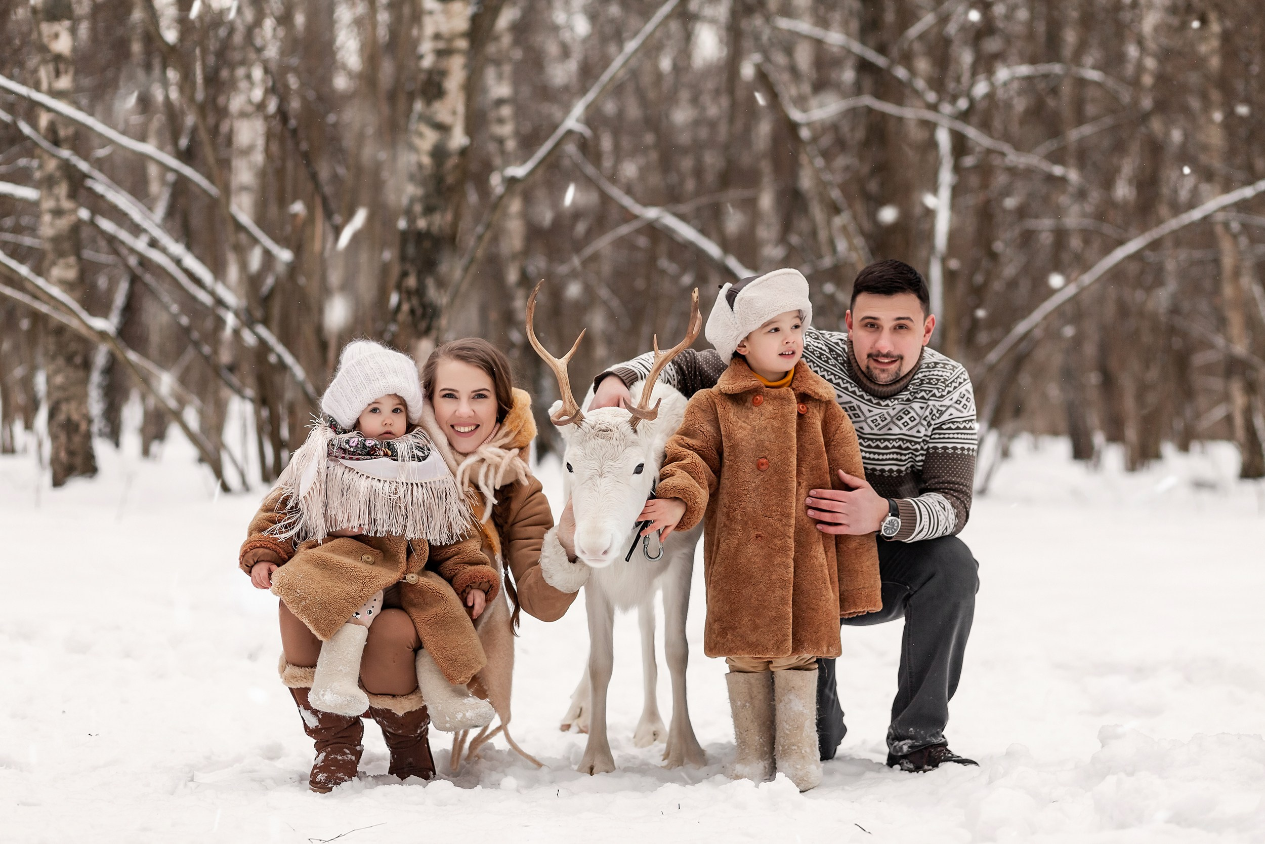 Фотосессия для родителей и детей с белым оленем в заснеженном лесу