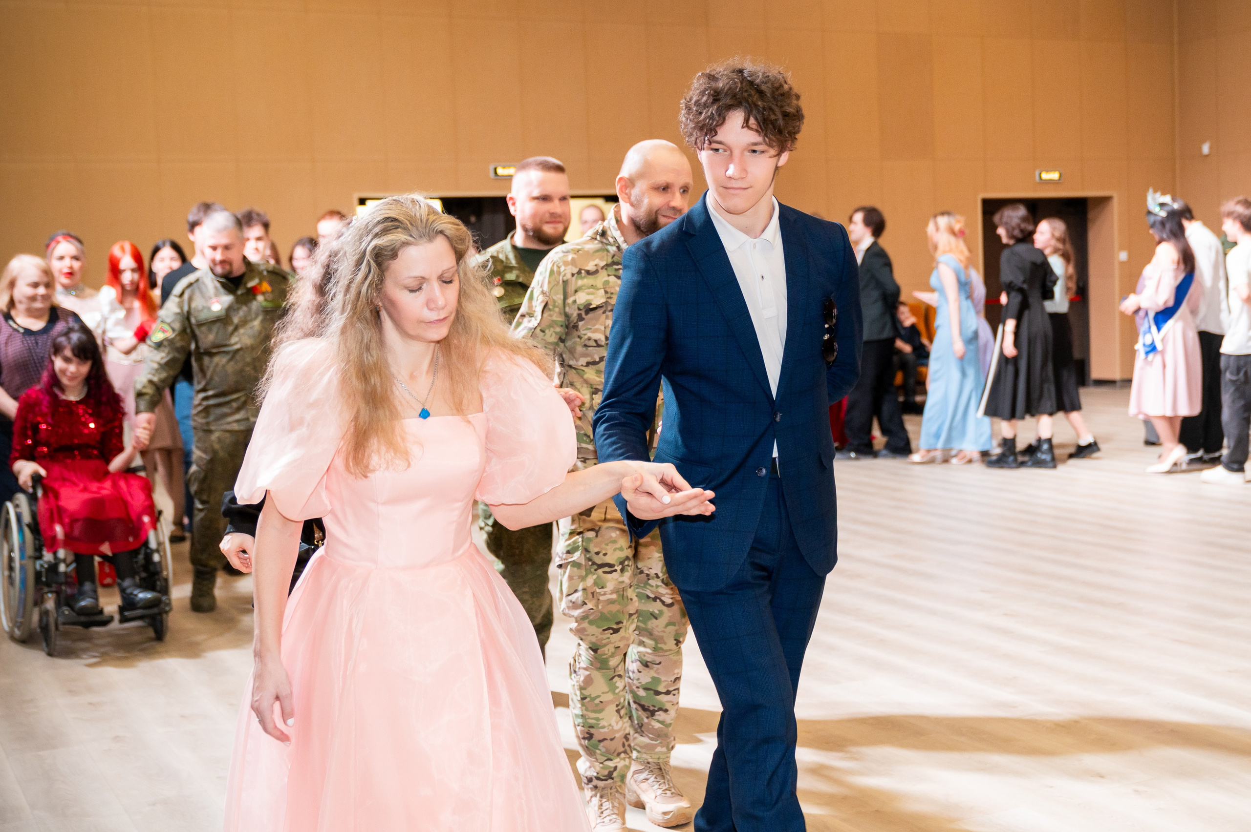 Молодая женщина в розовом платье и молодой человек в синем костюме танцуют на инклюзивном балу проекта «Мы все равны». Фото Мальцев Евгений.