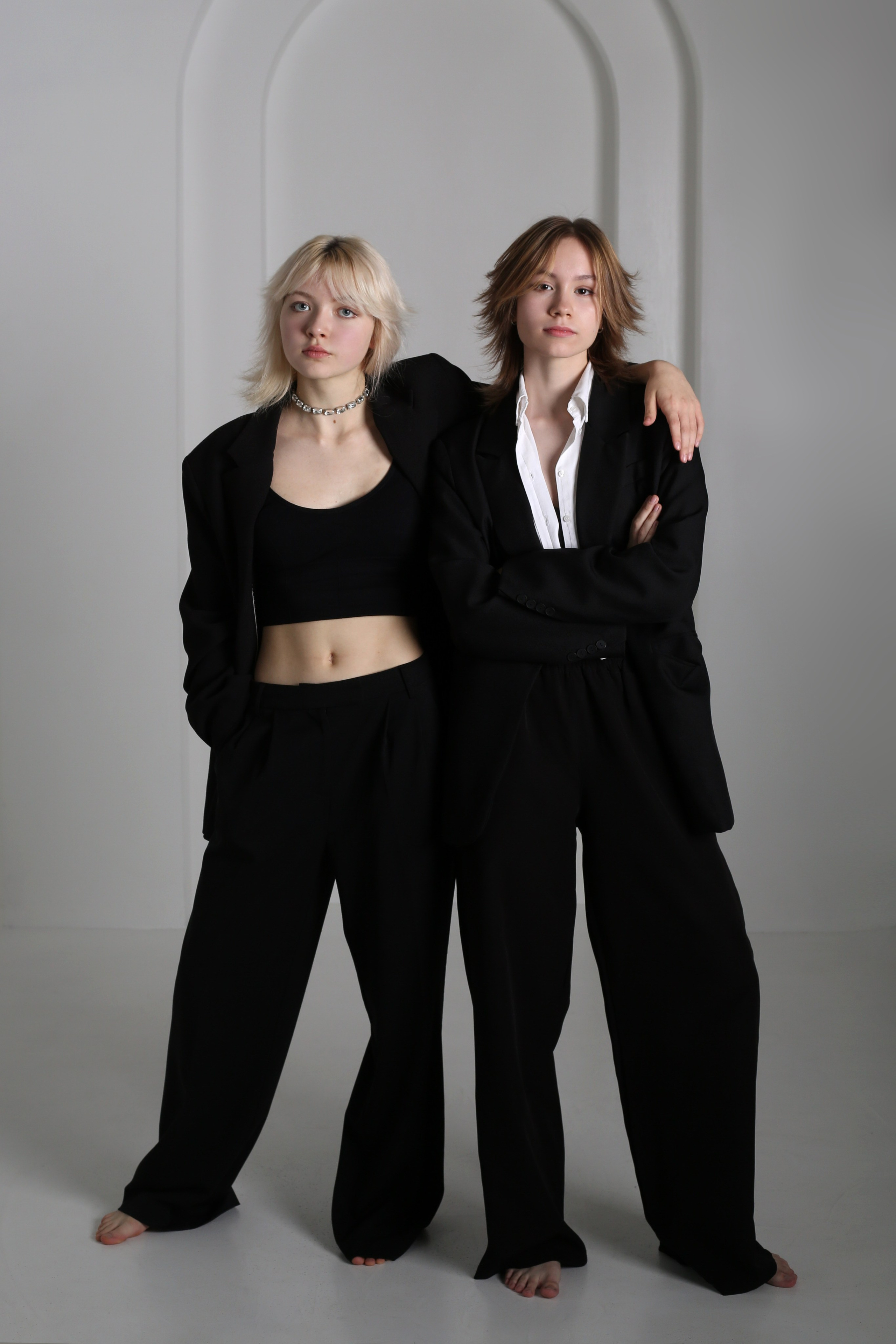 Студийная фотосессия «Геометрия»: две девушки в черных костюмах стоят на белом фоне