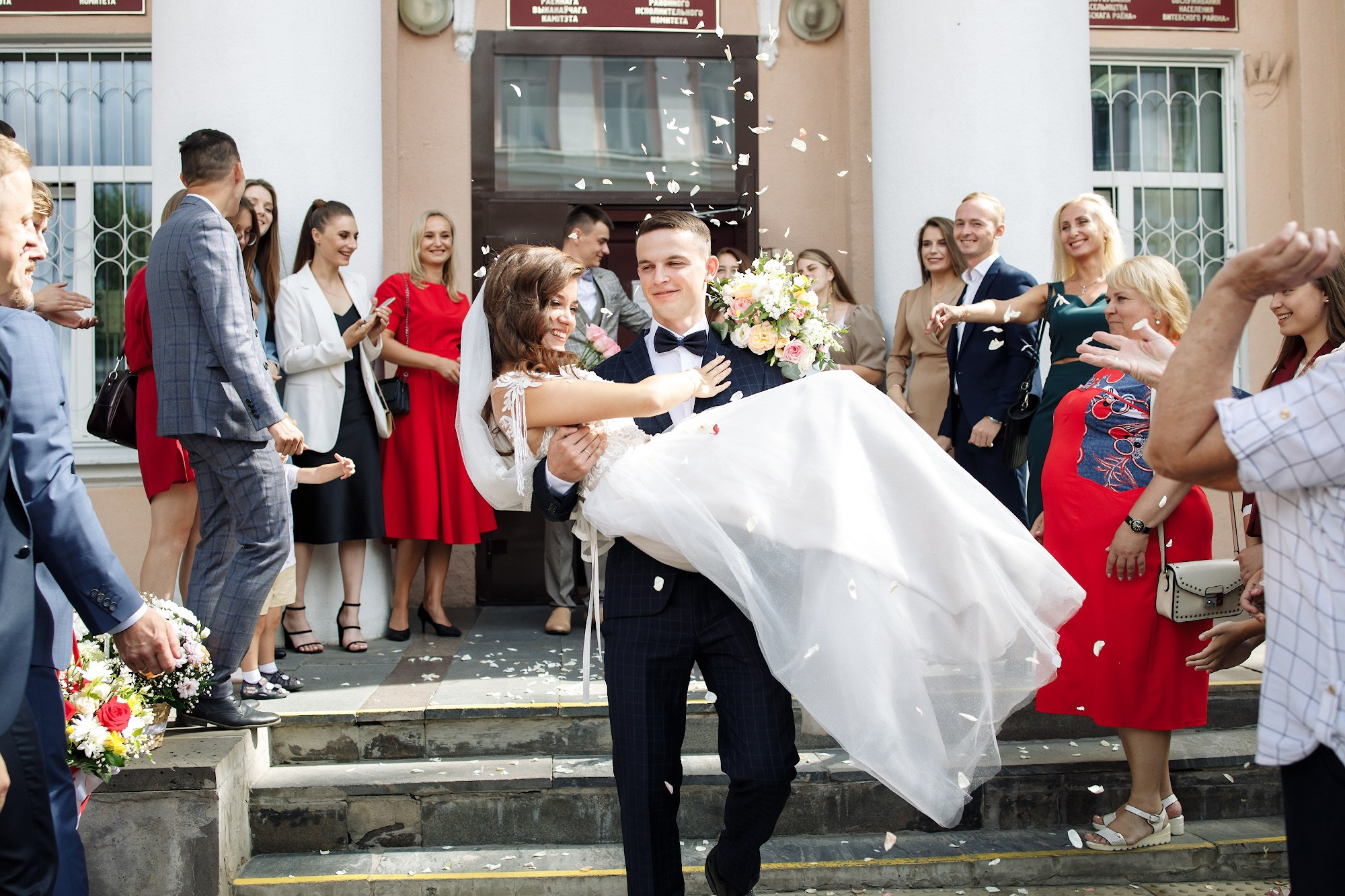 Жених выносит на руках невесту, а та очень радуется 