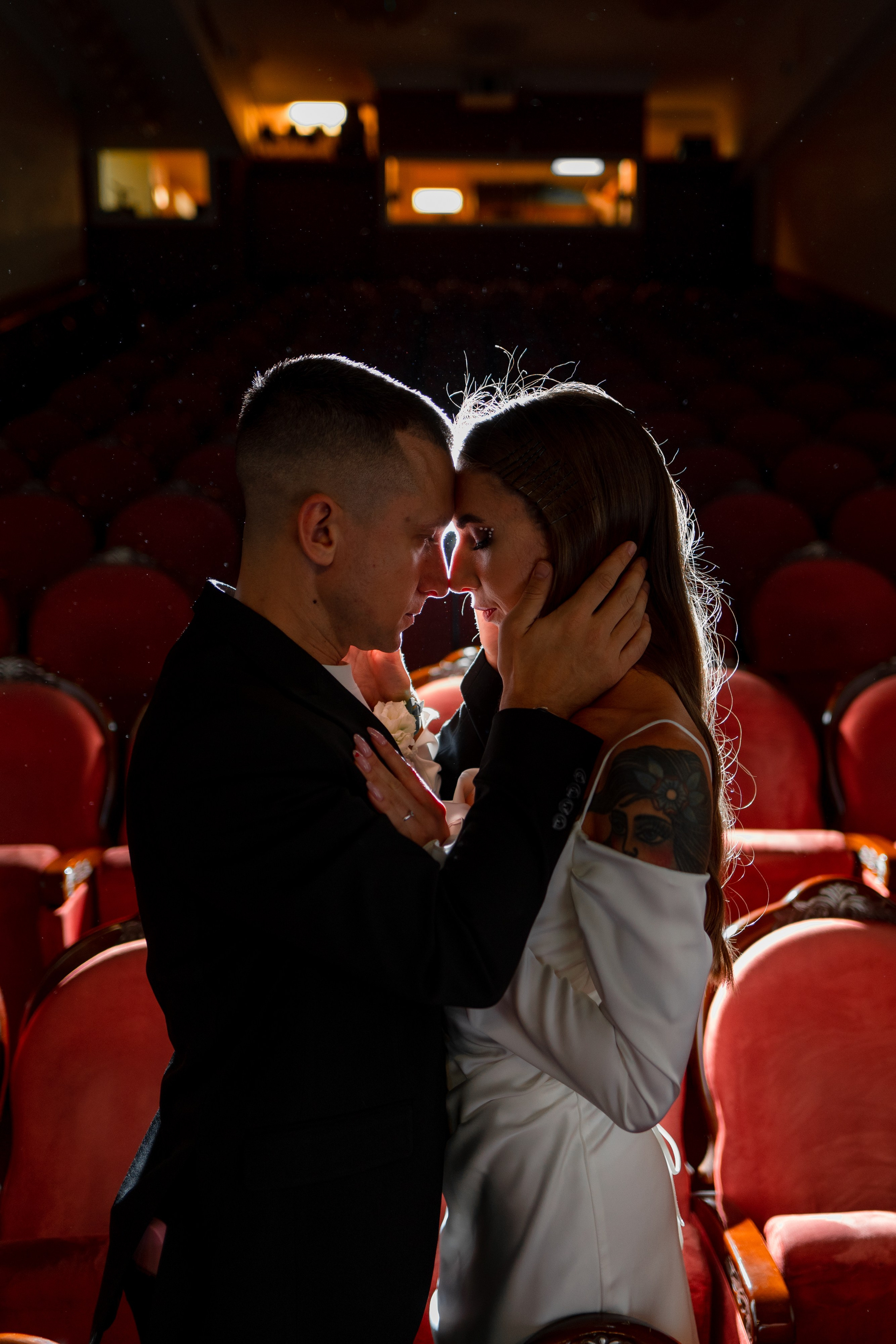 Жених и невеста целуются сидят в темном зале театра Андрея Миронова с красными креслами
