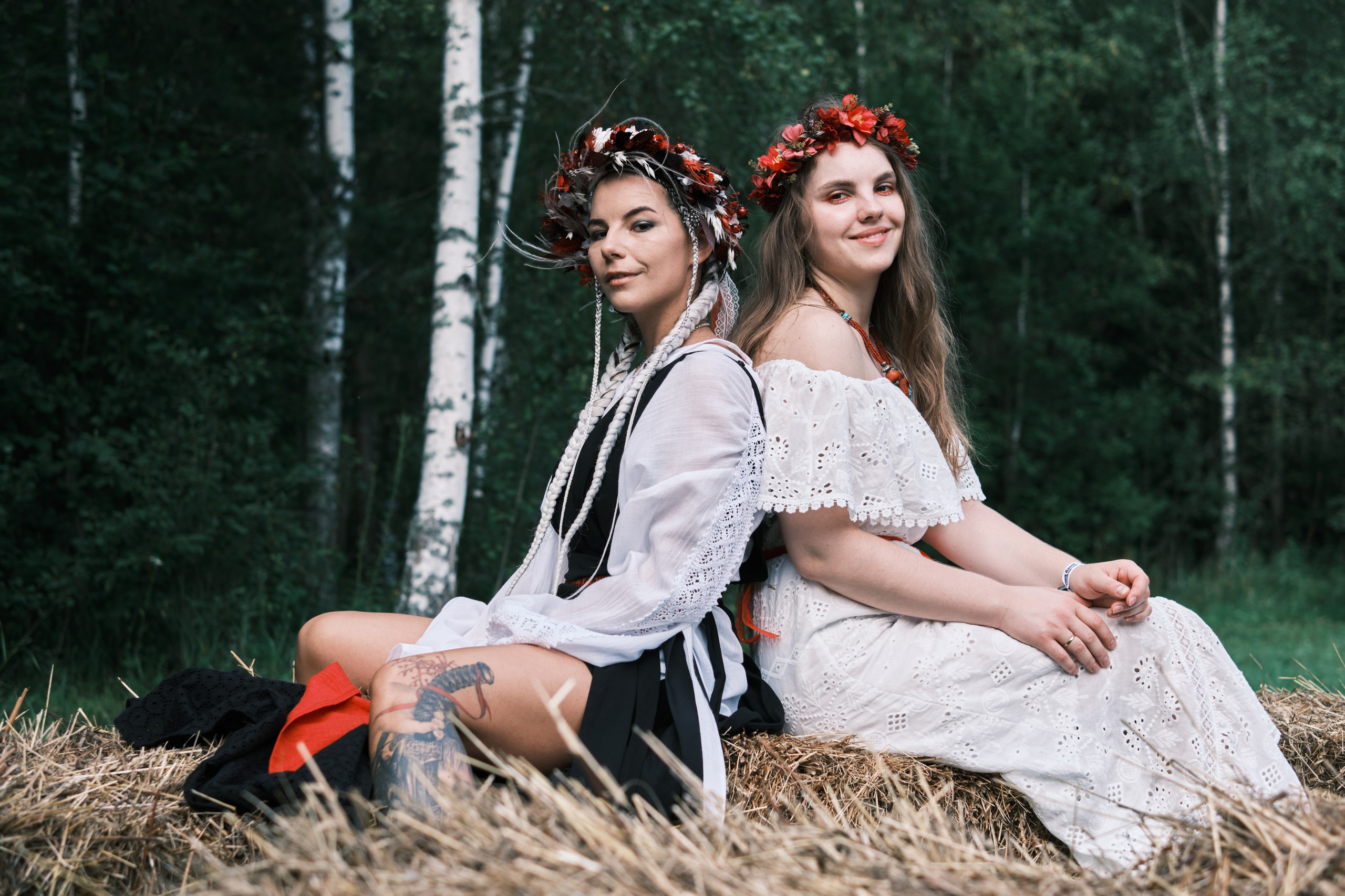 Девушки сидят на сене спина к спине,  в костюмах русский стиль