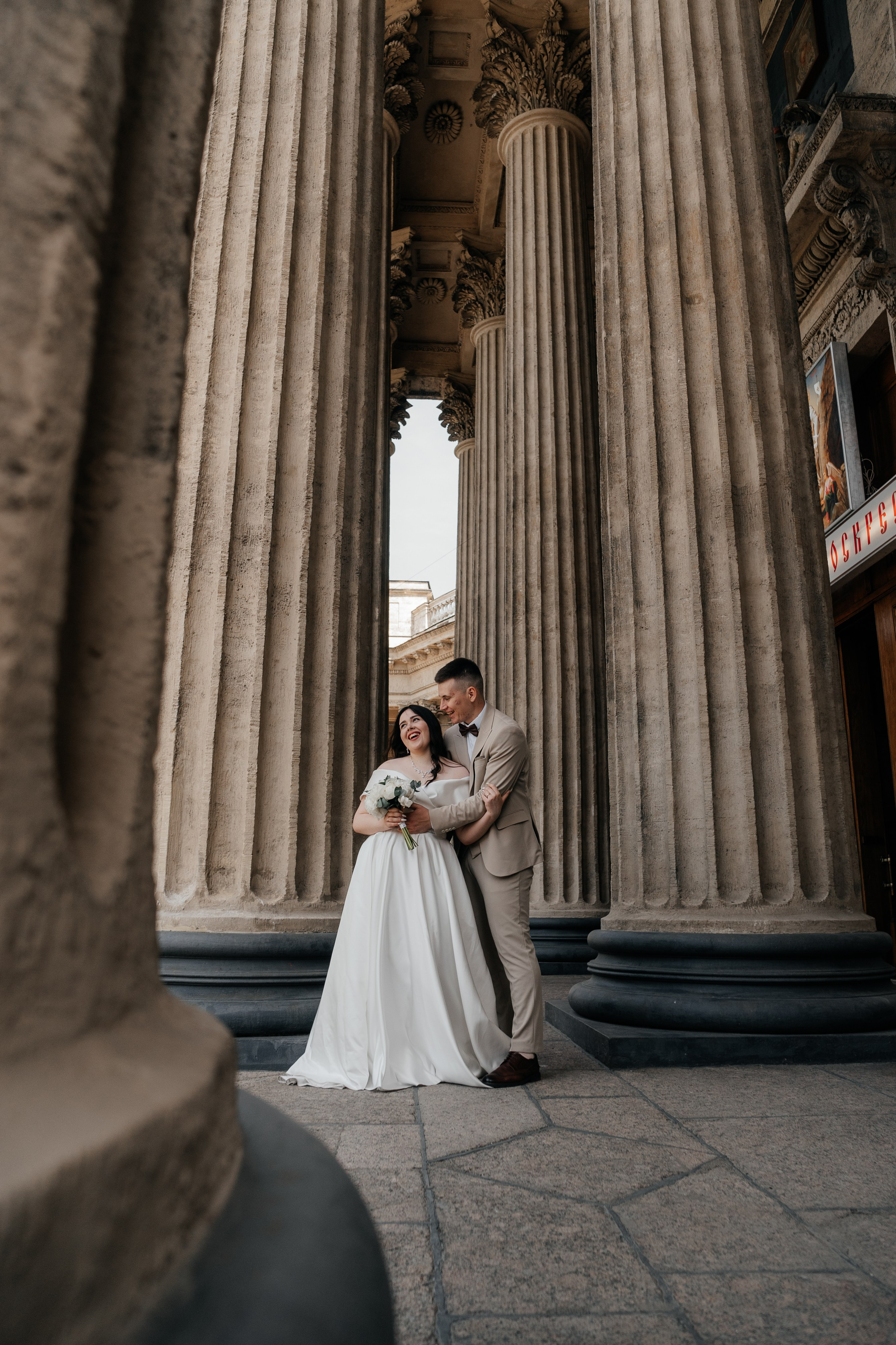 невеста смеется а жених ее обнимает среди колонн казанского собора