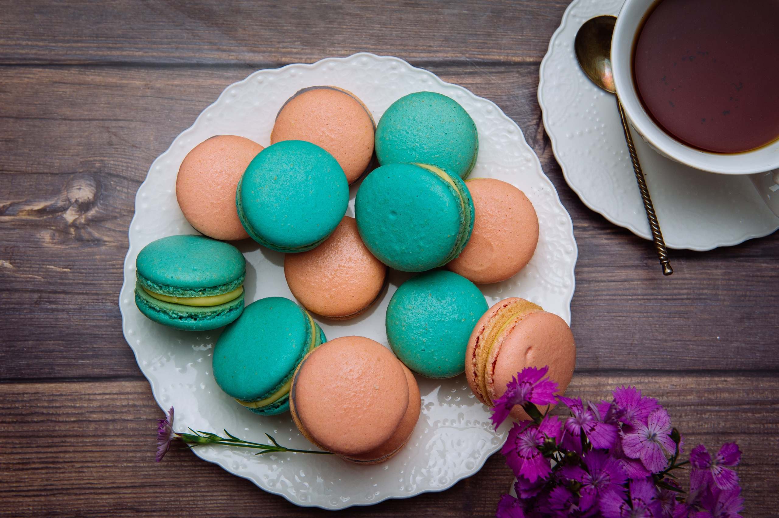 Вид сверху на пирожные макарон и чашку чая на столе, уютная композиция.